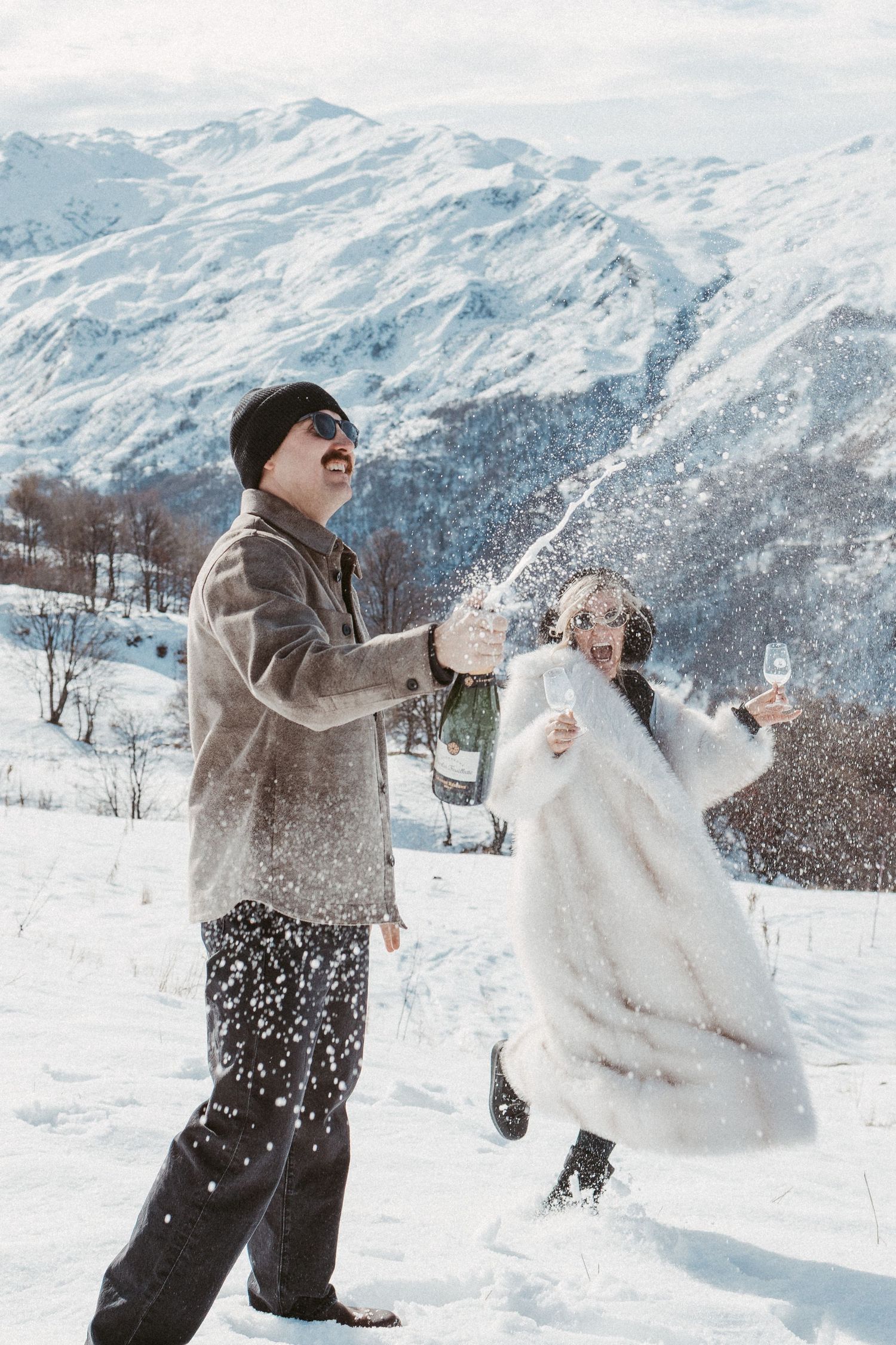 a newly engaged couple pops a bottle of champagne