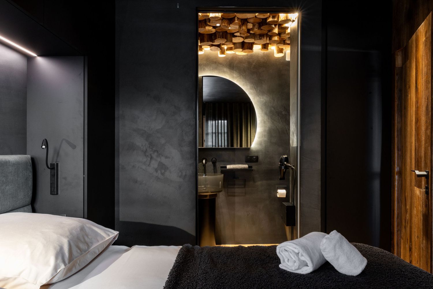 black bedroom with double bed and black bathroom