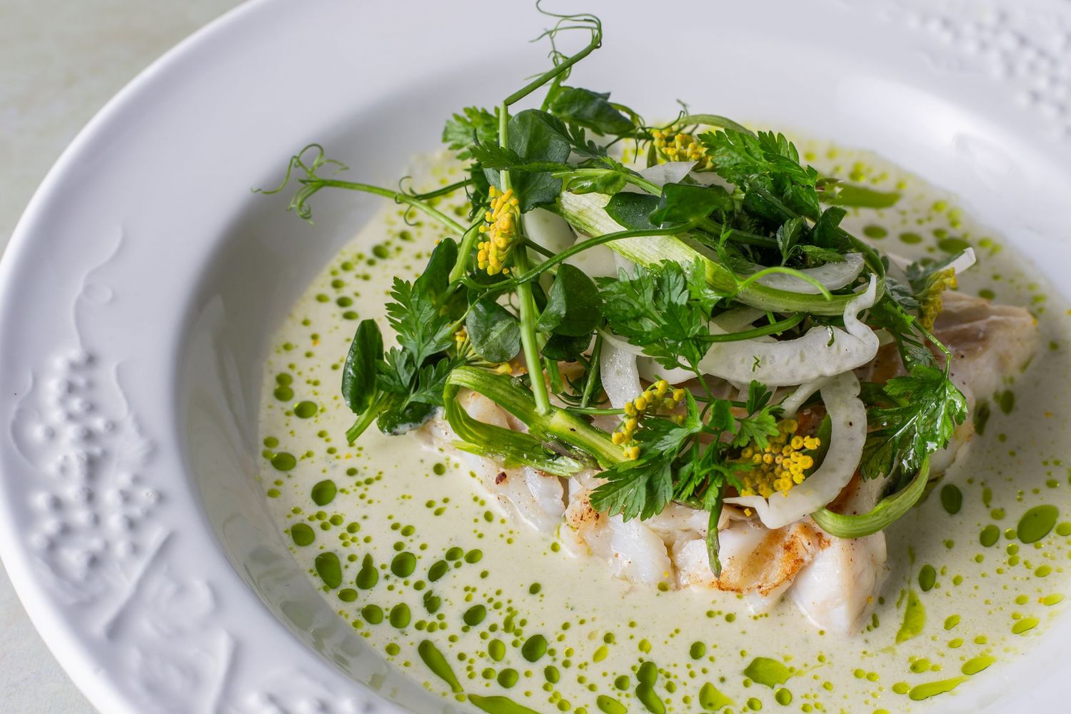 fish meal with parsley sauce served in an elegant white bowl