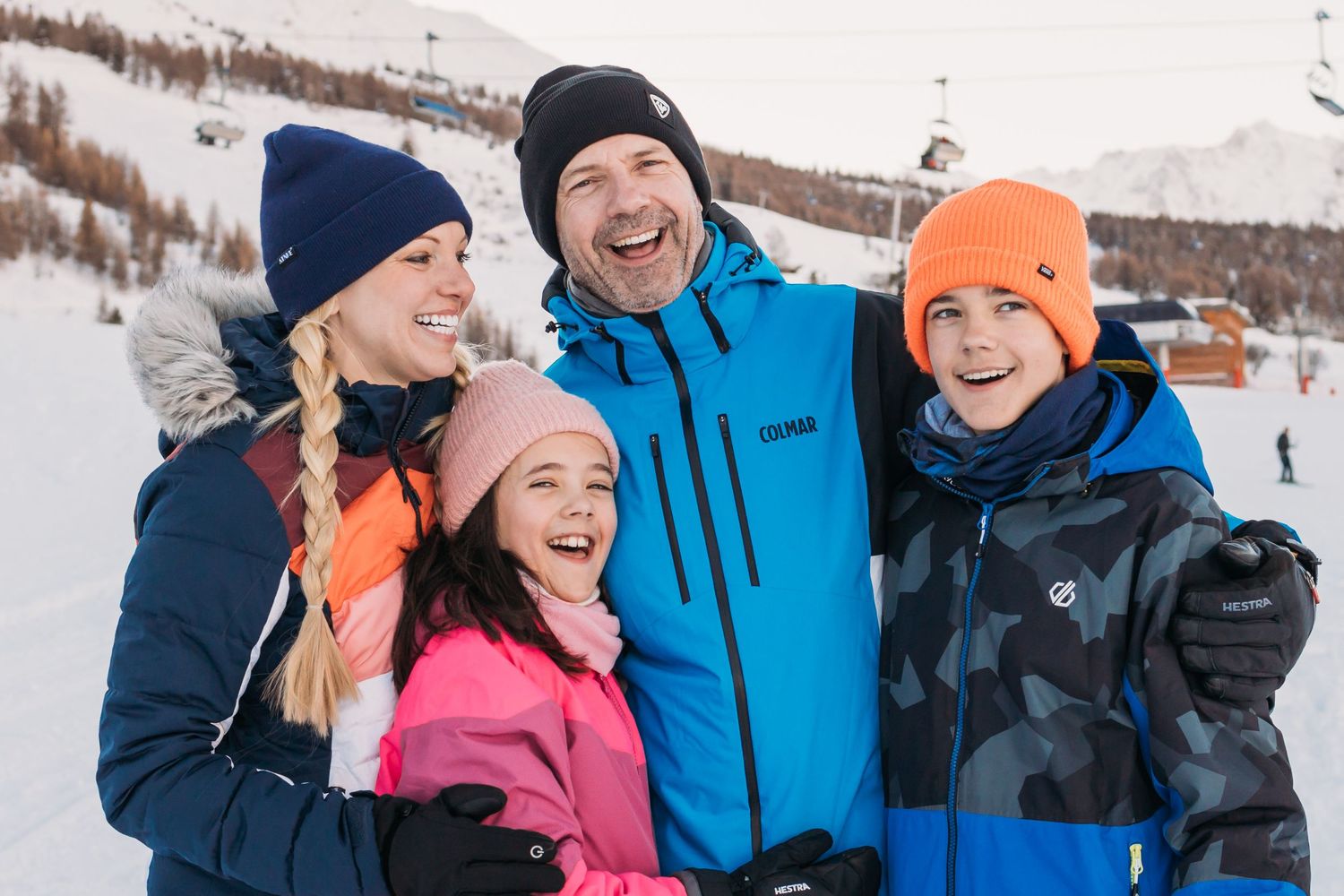 family laughing huddled together piste side in les arcs