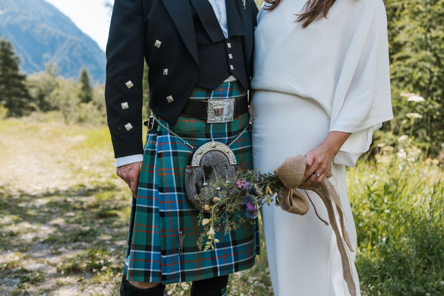 close up detail of spotting groom kilt and his brides dress and flowers