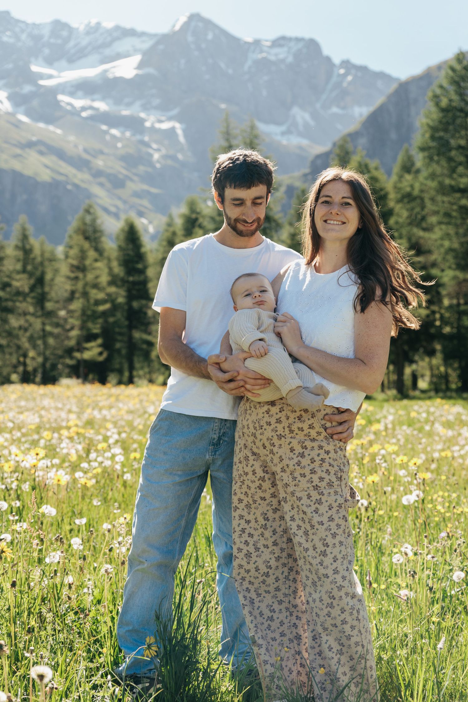 couple holds young baby in front of mountain