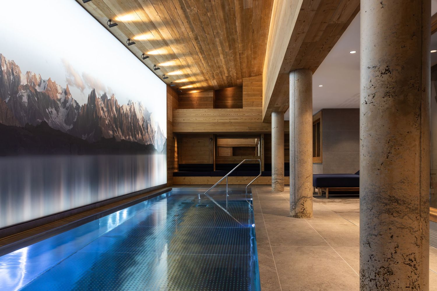 indoor pool with large mountain and forest artwork and concrete columns in ski chalet