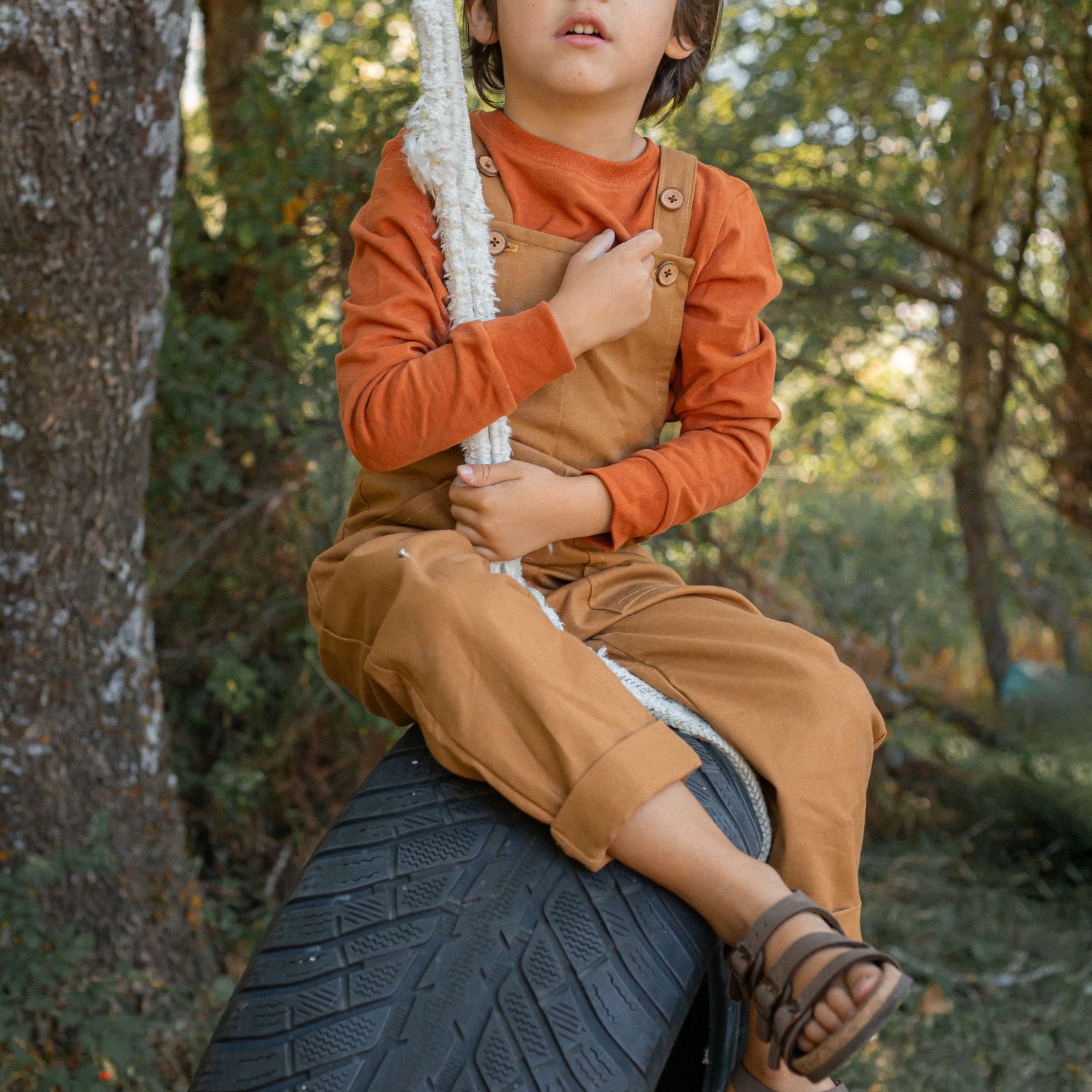 child sitting on tyre swing in garden