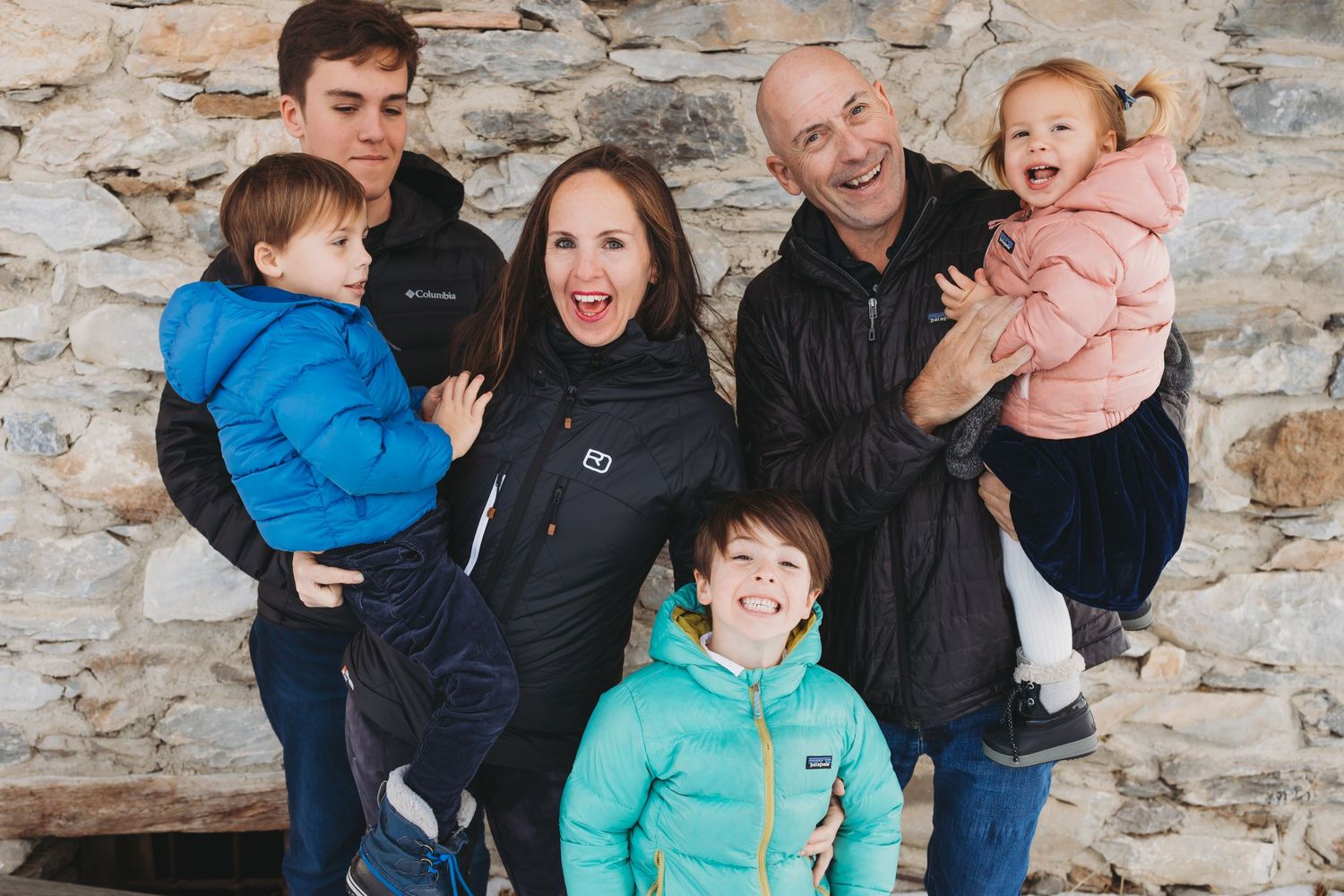 family of 6 smiling and happy infant of alpine building