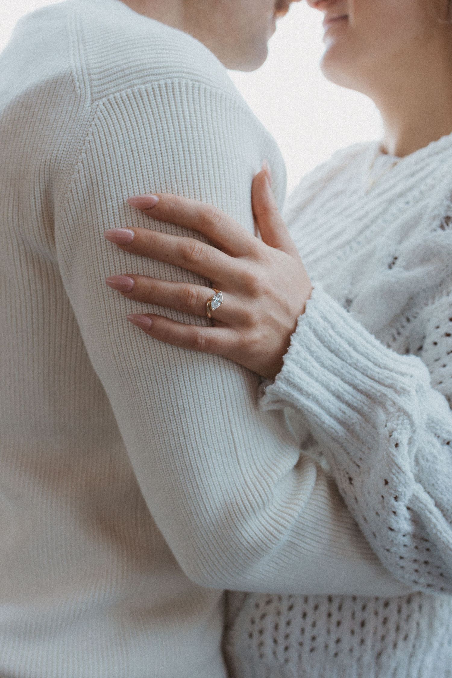 woman rests hand on mans upper arm with engagement ring on display