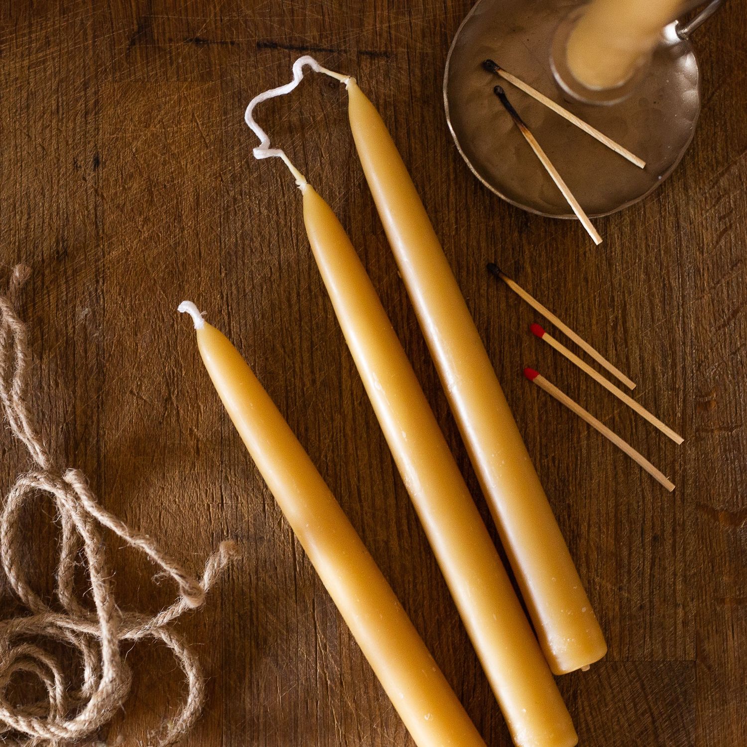 wax candle sticks laying on table with candle stick holder and matches