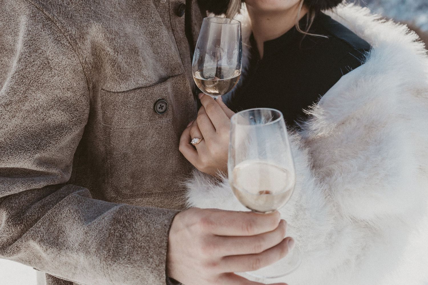 close up of champagne glass being held by newly engaged couple