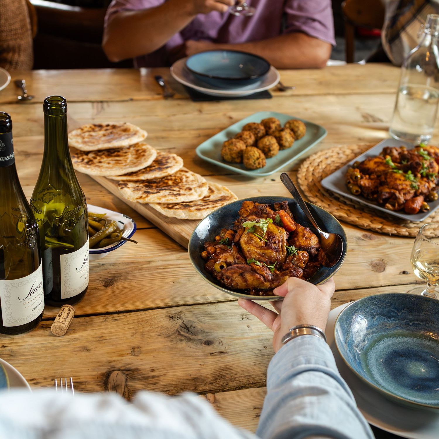 man passes bowl of food across table to friend