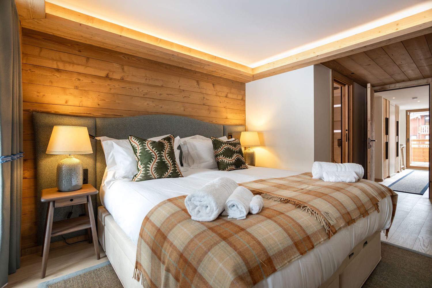large sumptuous bed in ski chalet with ceiling strip lighting