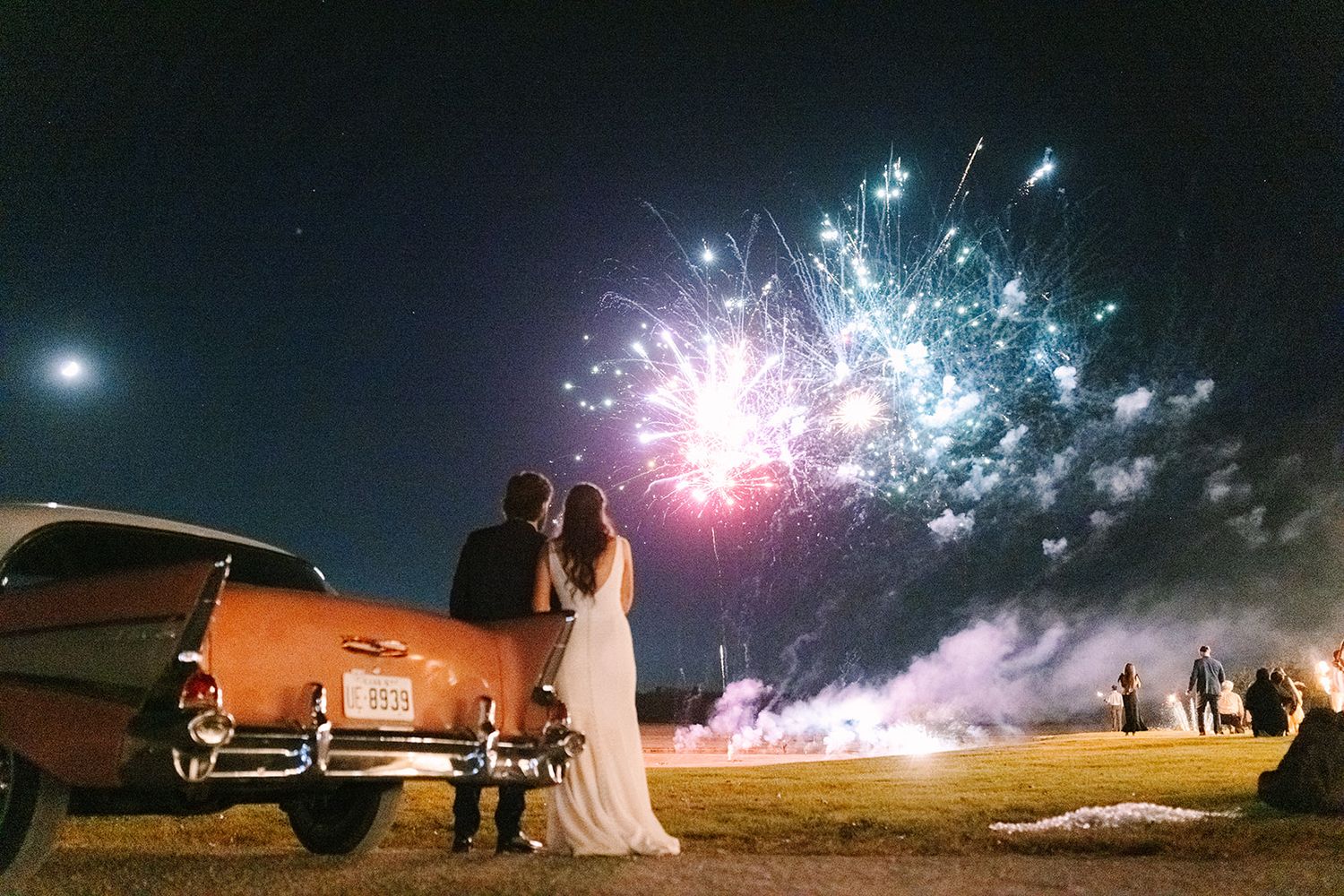 Collage of silhouetted figures against night sky with bright fireworks displays and classic cars creating romantic moments.