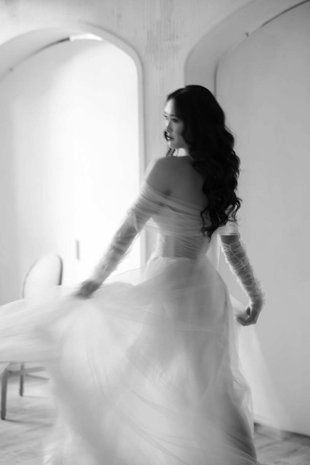 Bride twirling in her wedding gown, showcasing the dress’s flow and elegance in a softly lit room. Taken by a Toronto we