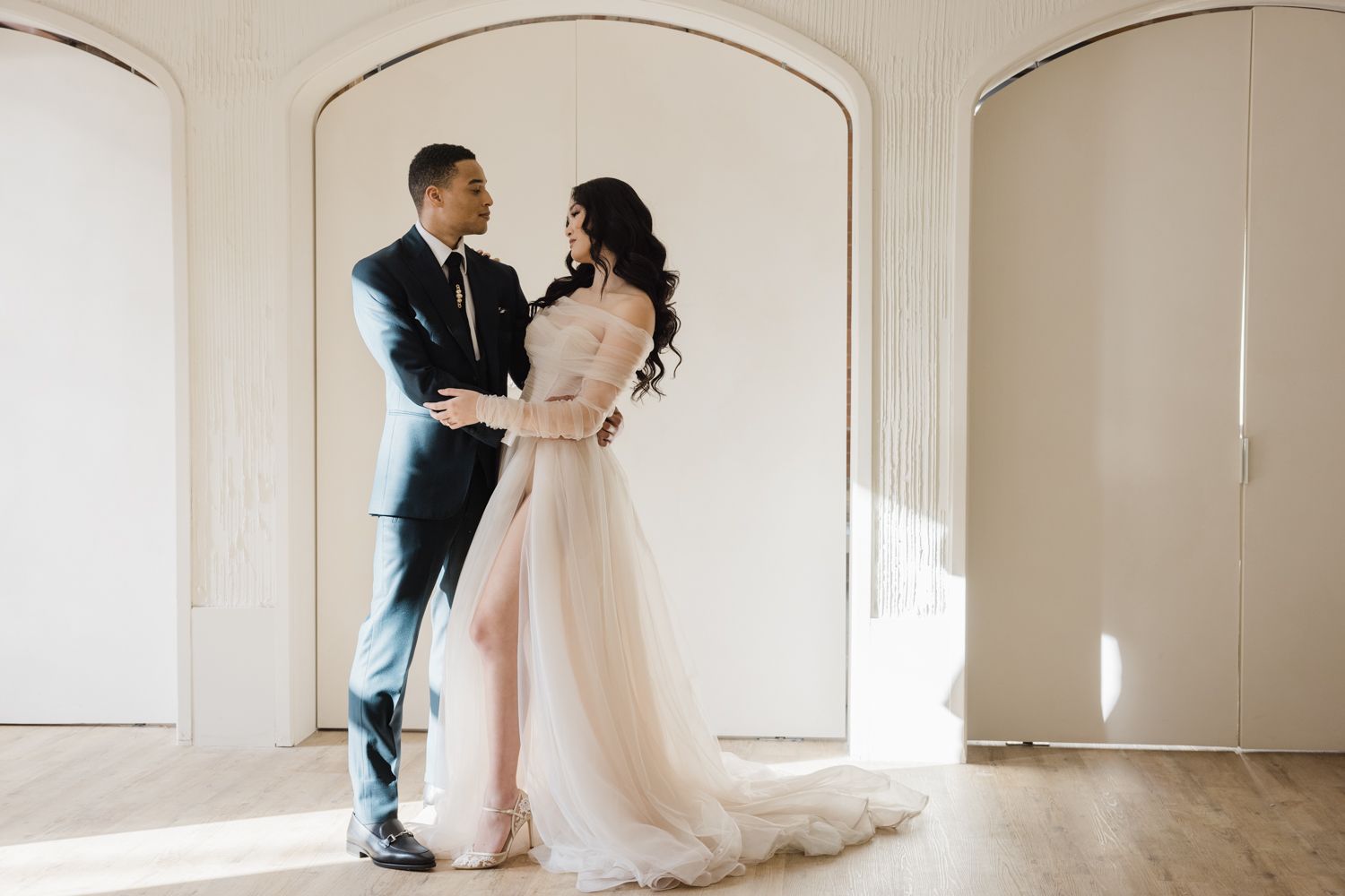 Newlyweds sharing a tender embrace in front of elegant archways, highlighting the couple’s love. Photographed by a Toron