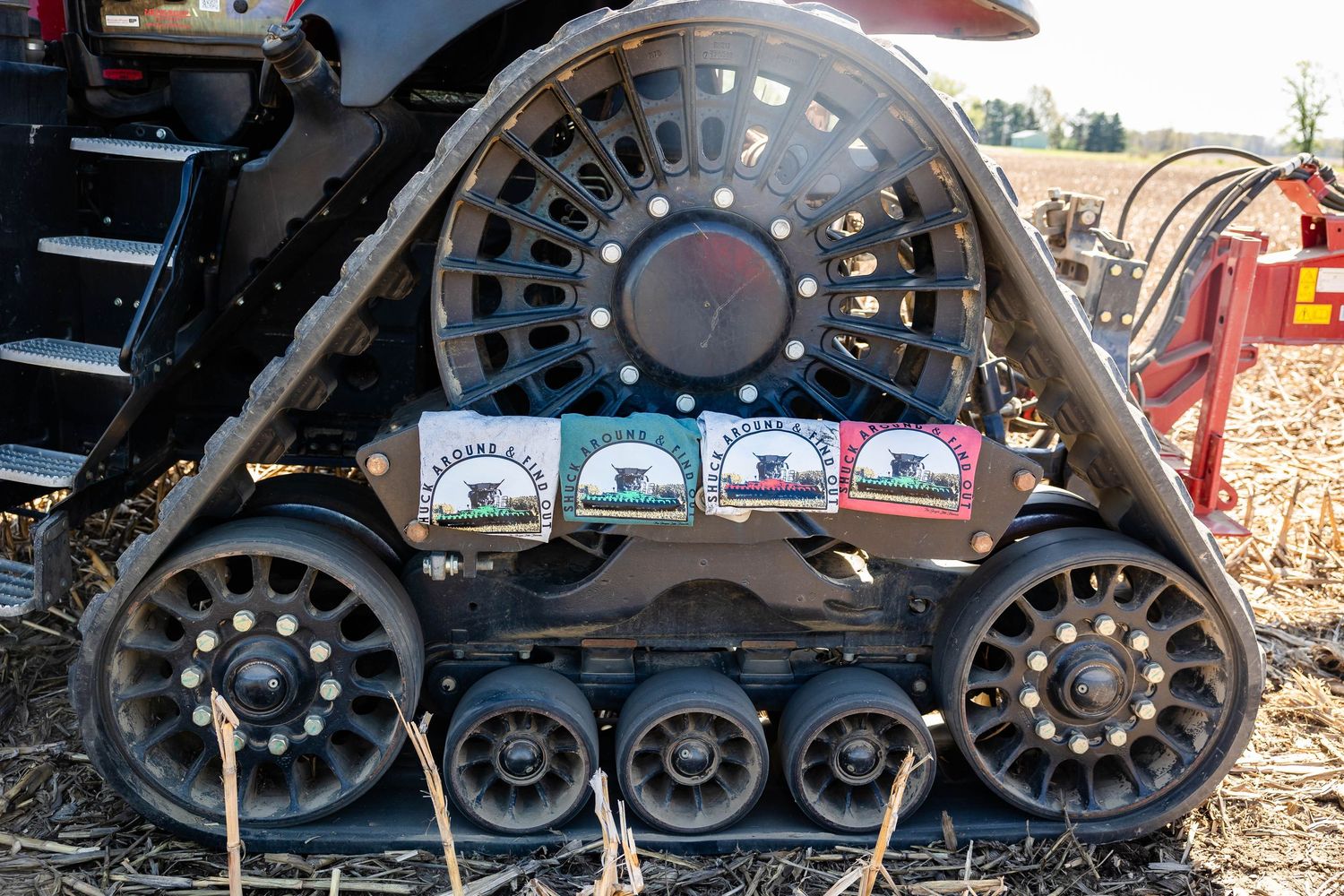 Close-up of a large agricultural tractor track with seed packets displayed on it in a farm field.