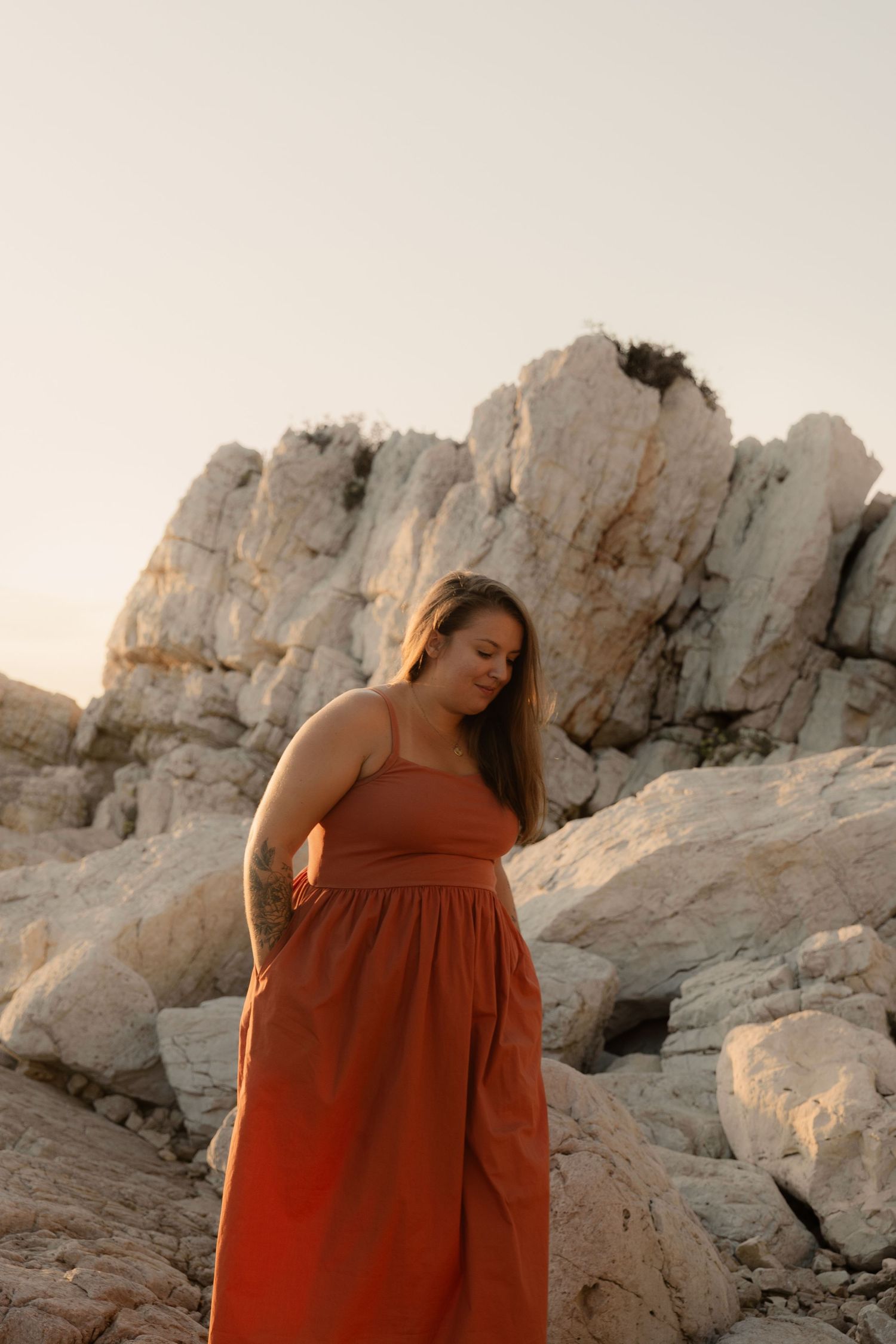 Femme habillée d'une robe orange marchant dans les rochers des graillons à juans les pins