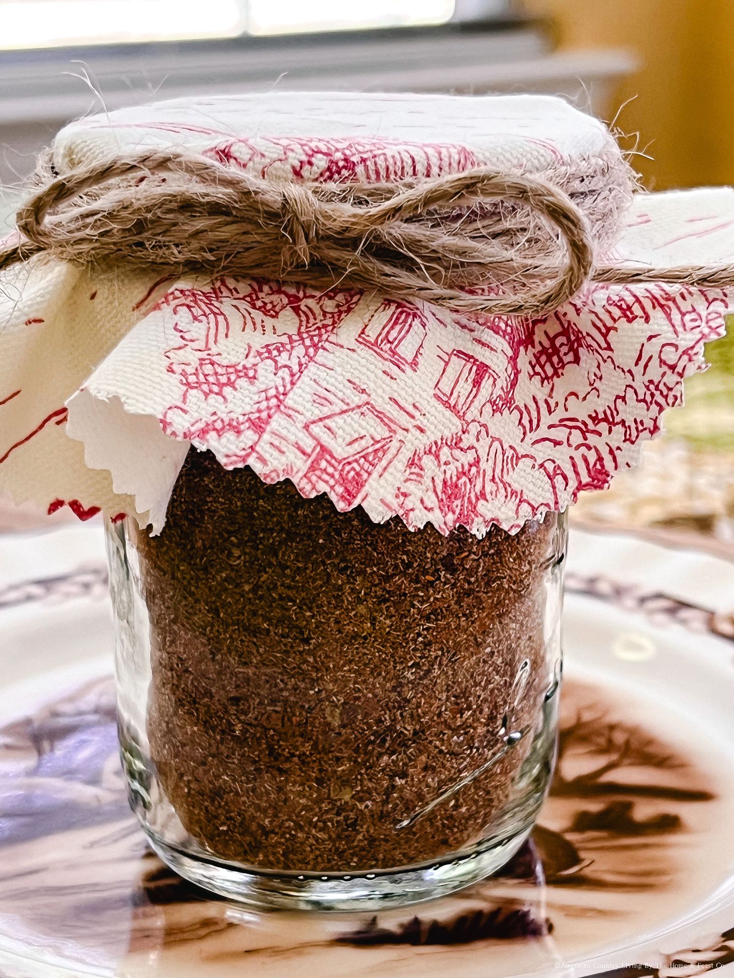 Glass jars filled with chocolate cake mix layered with red and white checkered fabric covers.