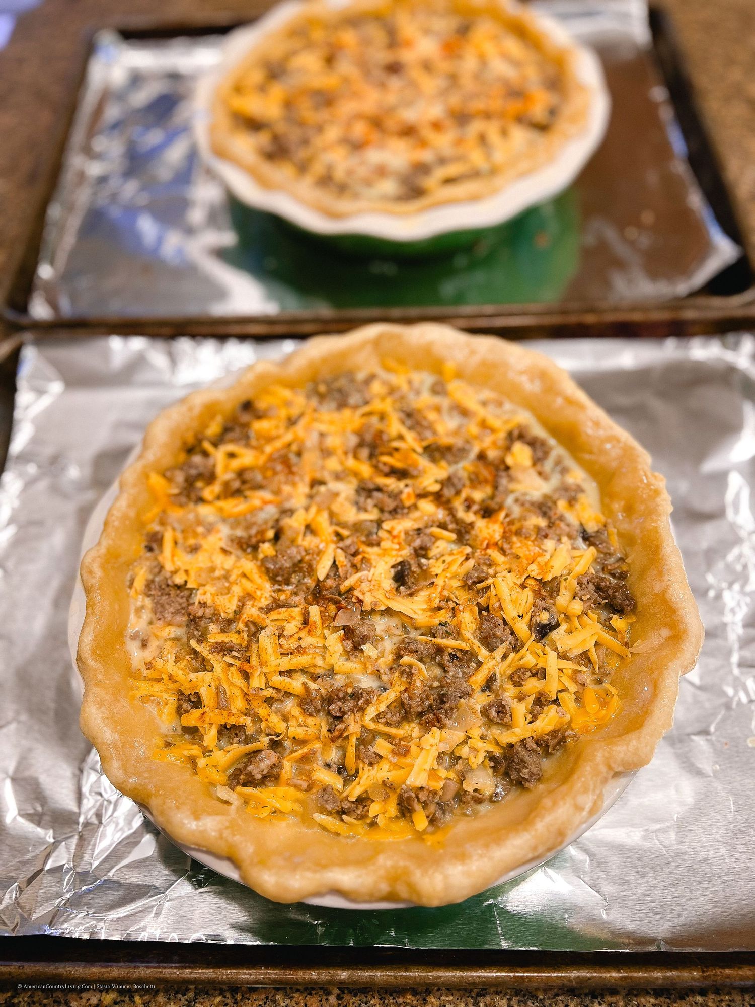 Savory meat pies with melted cheese topping arranged on a baking sheet.