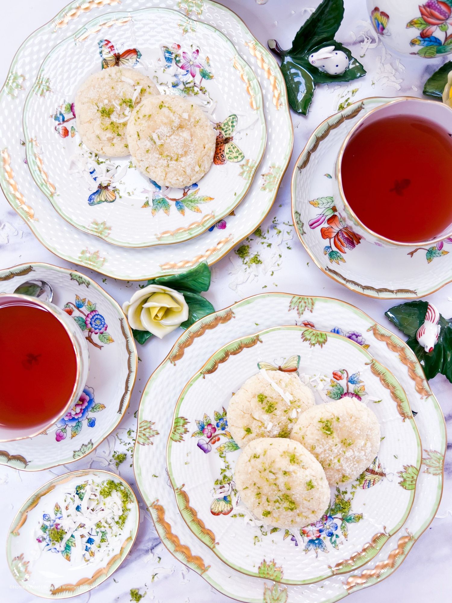 Overhead view of vintage floral plates with pastries and tea service.