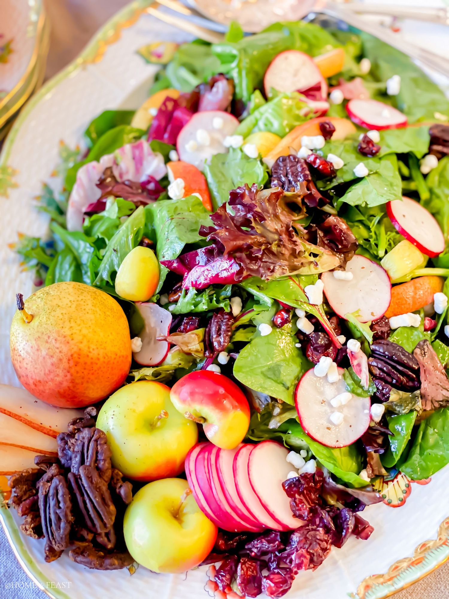 Vibrant fall salad featuring fresh apples, mixed greens, and dried fruits on decorative dinnerware.