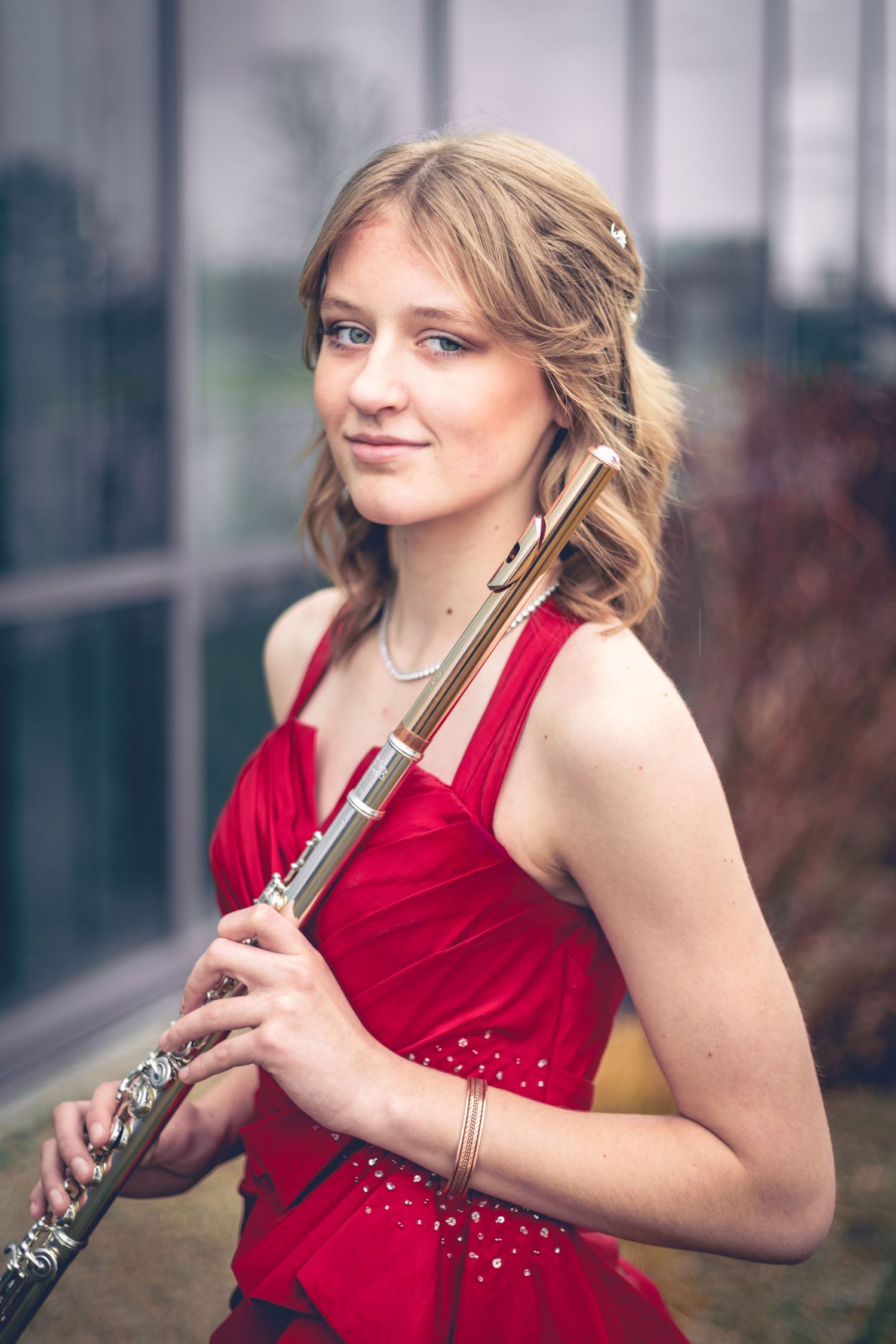 A person wearing a red dress stands outdoors, holding a flute, ready for dynamic portraits.