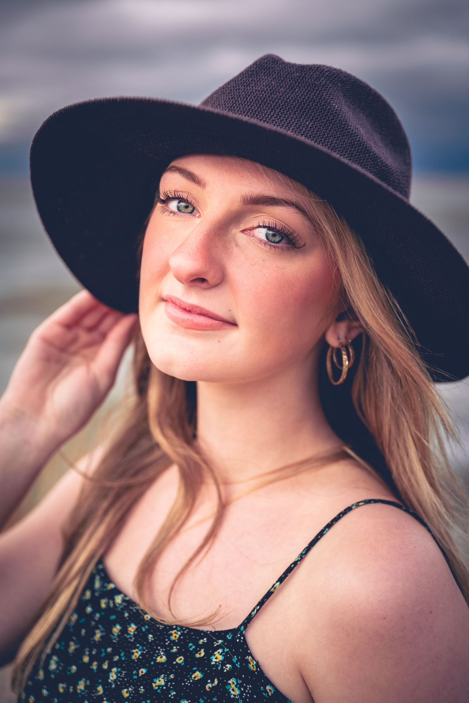 Young woman with a black hat smiling gently at the camera for her personalized graduation portrait