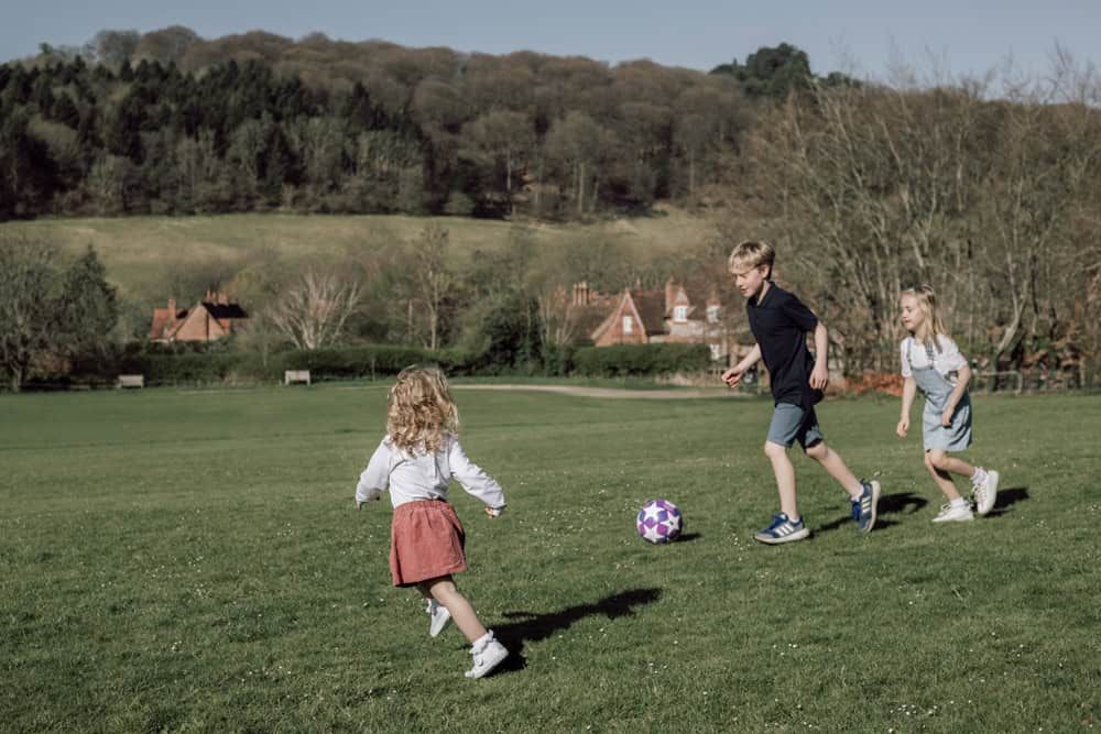 Some children play football and laugh together in Hambleden valley.