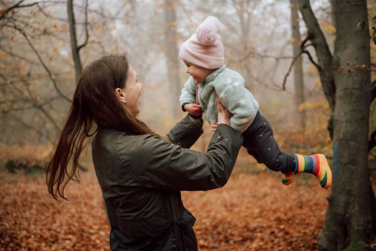 A mother twirls her laughing toddler around on a misty morning in Marlow Common.