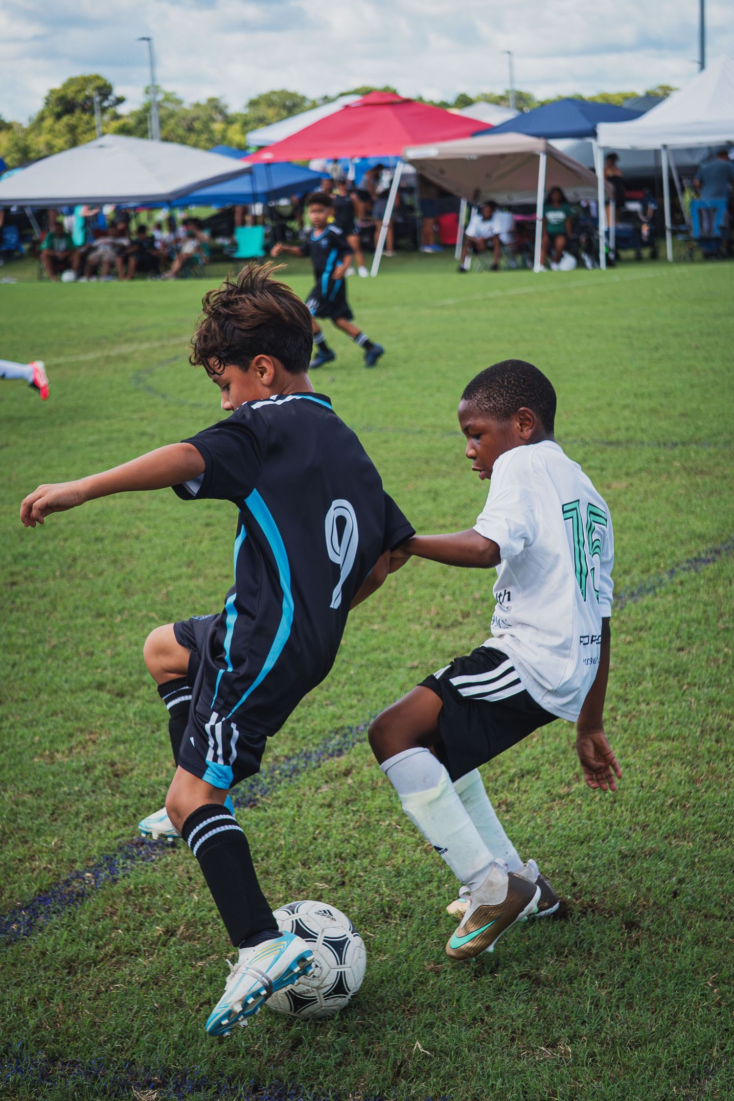 Two youth soccer players competing for the ball during an outdoor soccer tournament game.