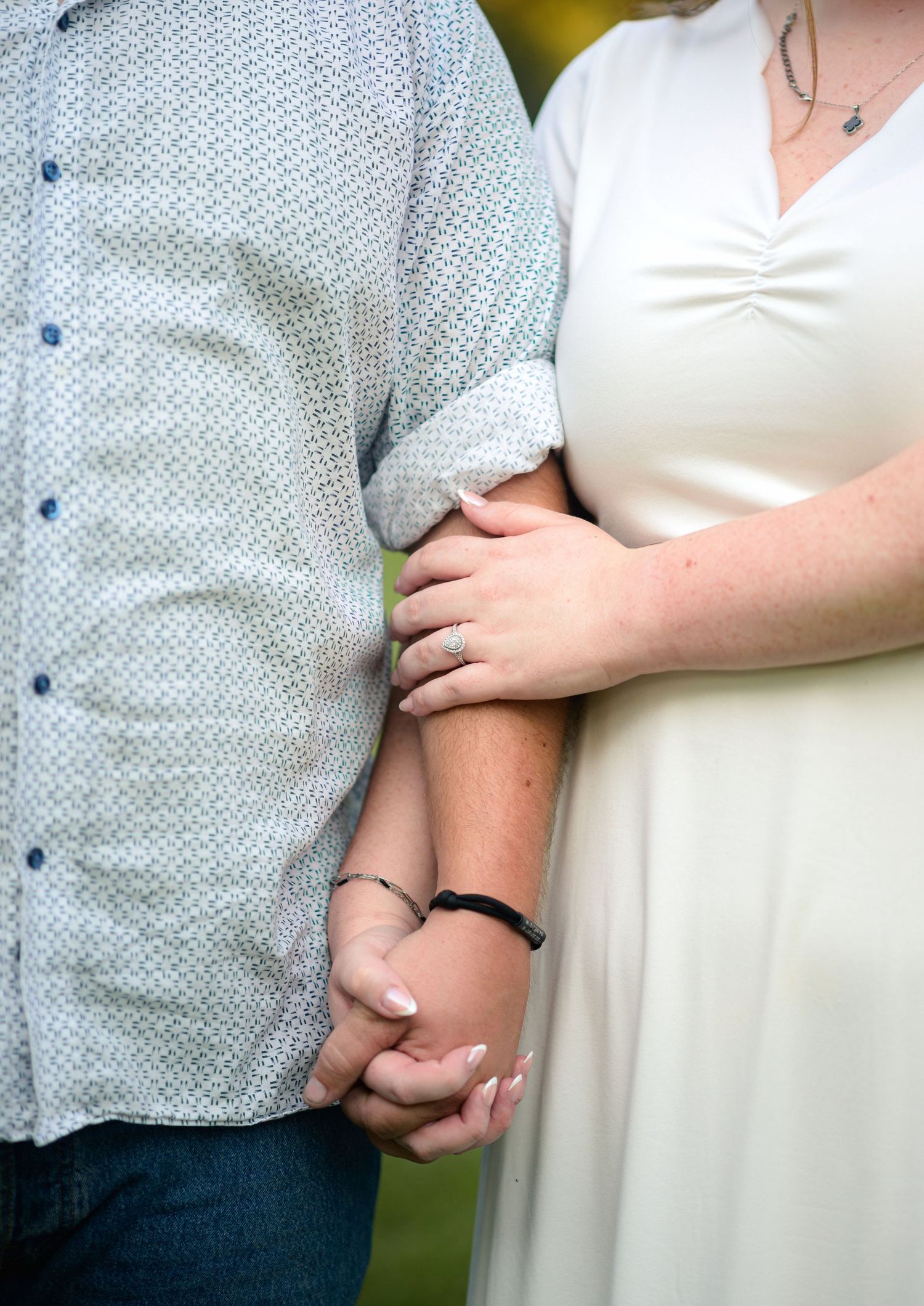 Close-up of engaged couple holding hands, showcasing a sparkling diamond engagement ring.