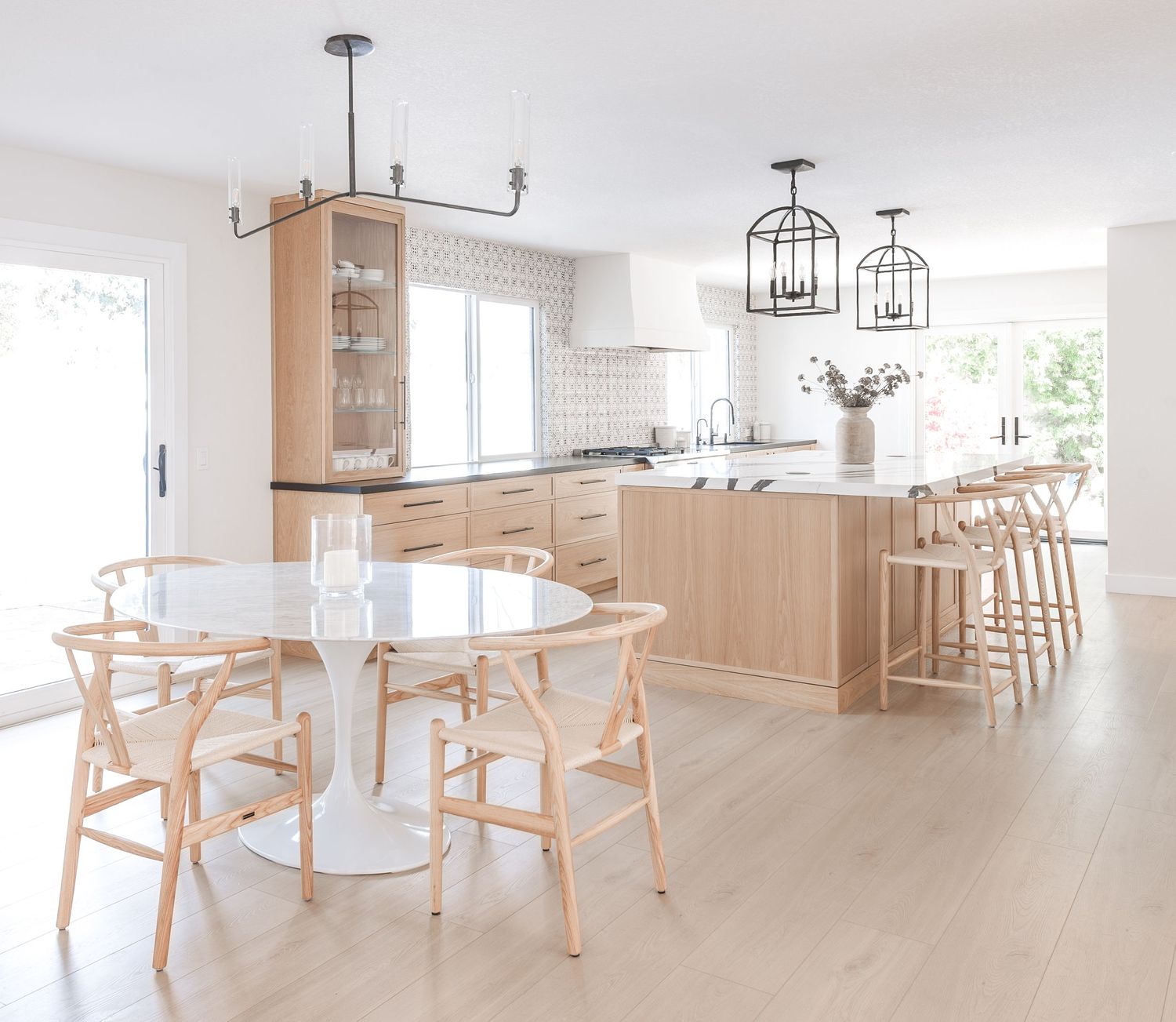 Bright open dining space with natural wood furniture and black pendant lighting fixtures photographed by an SoCal interior photographer.