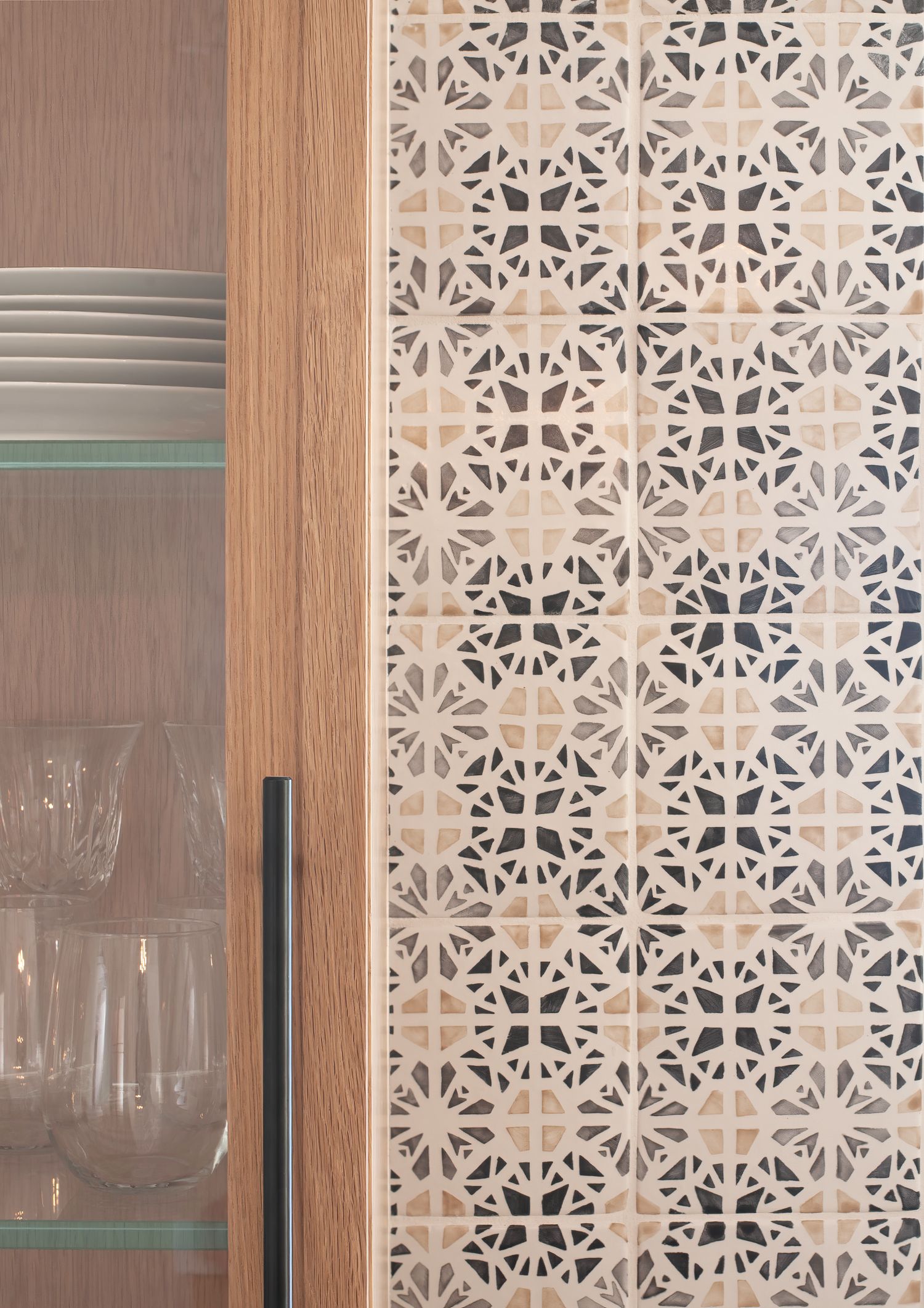 Interior photo of modern kitchen cabinets and  decorative geometric pattern backsplash tiles.