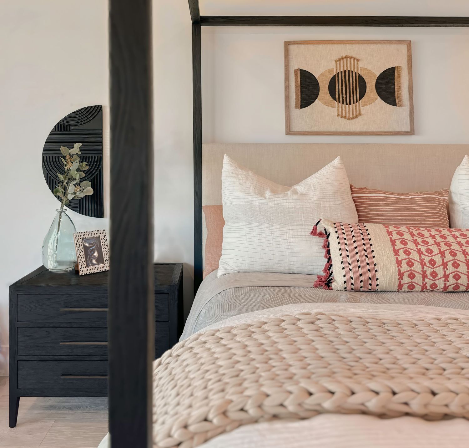 Serene bedroom featuring chunky knit blanket, pink accents, and modern wall art.