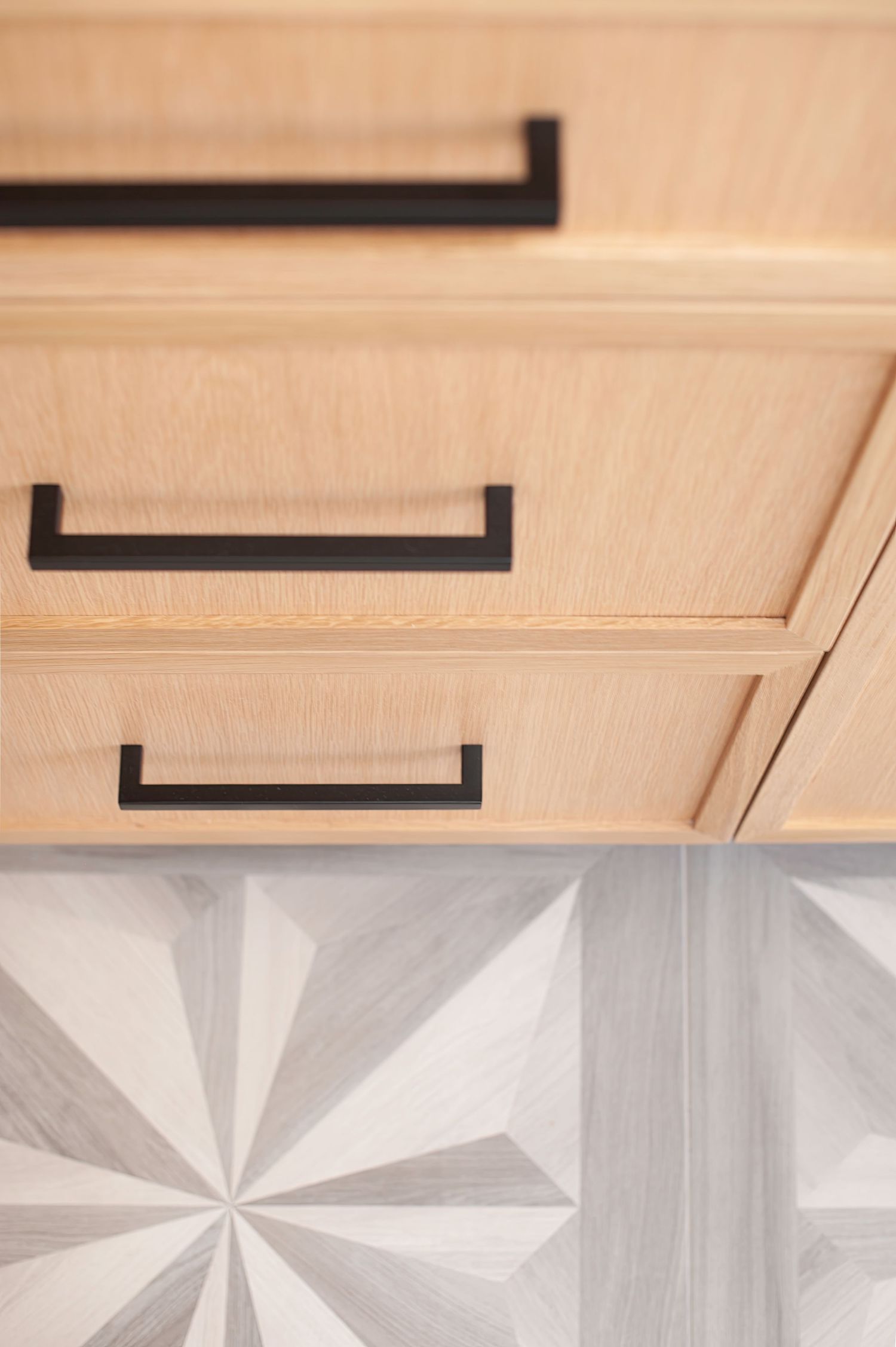 Close-up of wooden cabinetry with black hardware and geometric floor tile pattern shot by SoCal interior photographer.