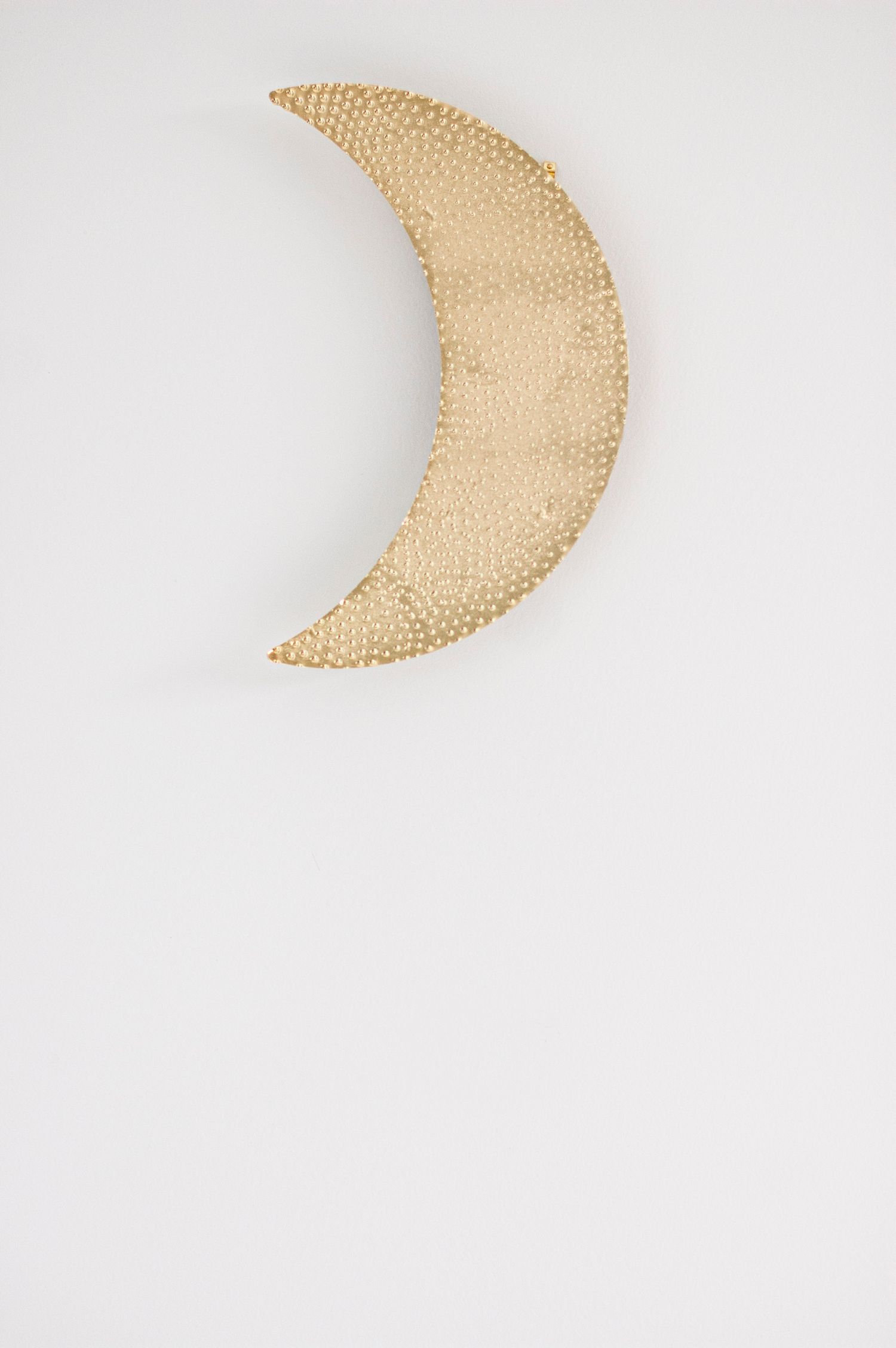 Woven moon-shaped wall decoration photographed against a white background.