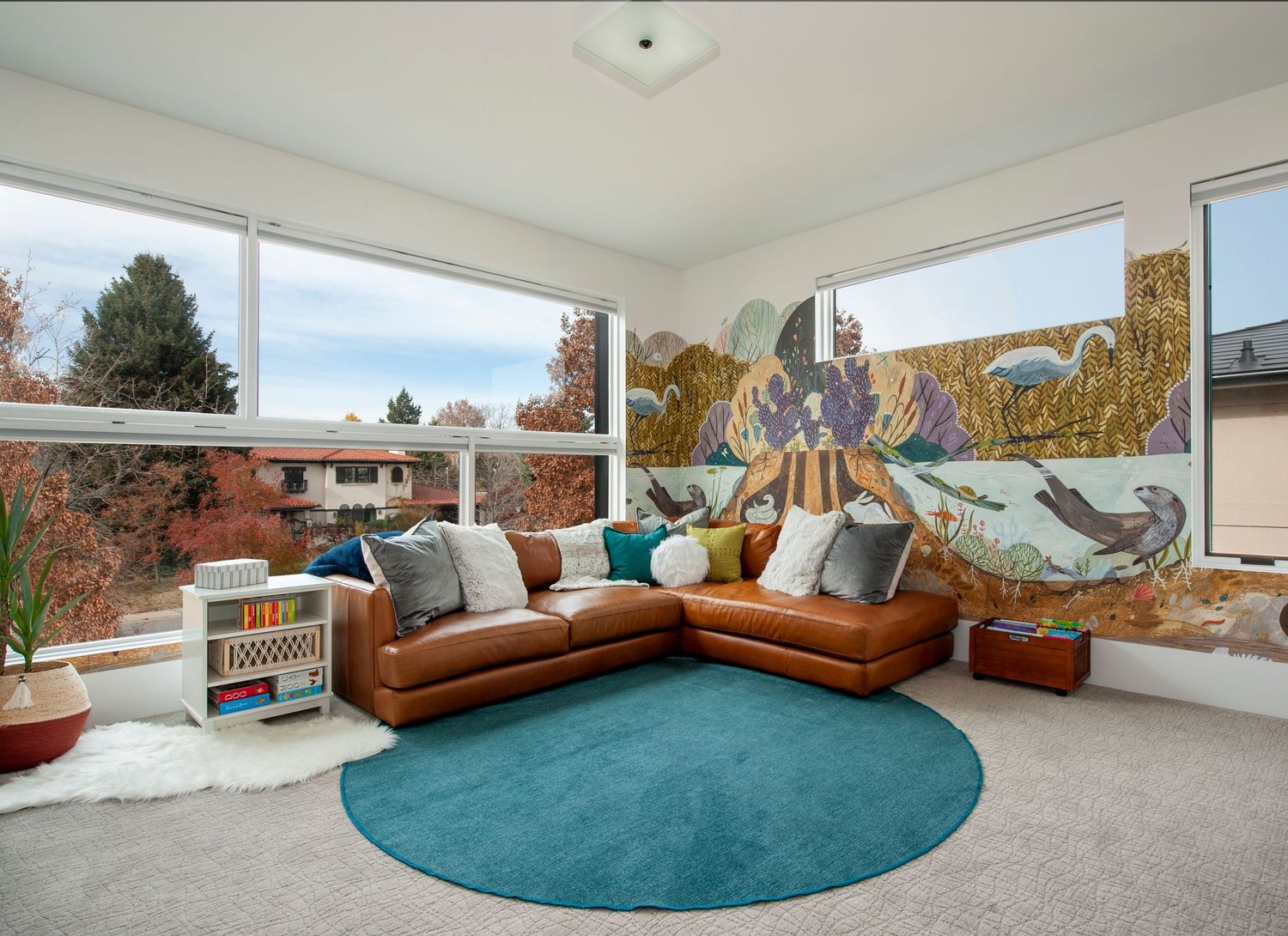 Mid-century modern play room with leather sectional and turquoise rug overlooking mountain views in Denver Colorado.