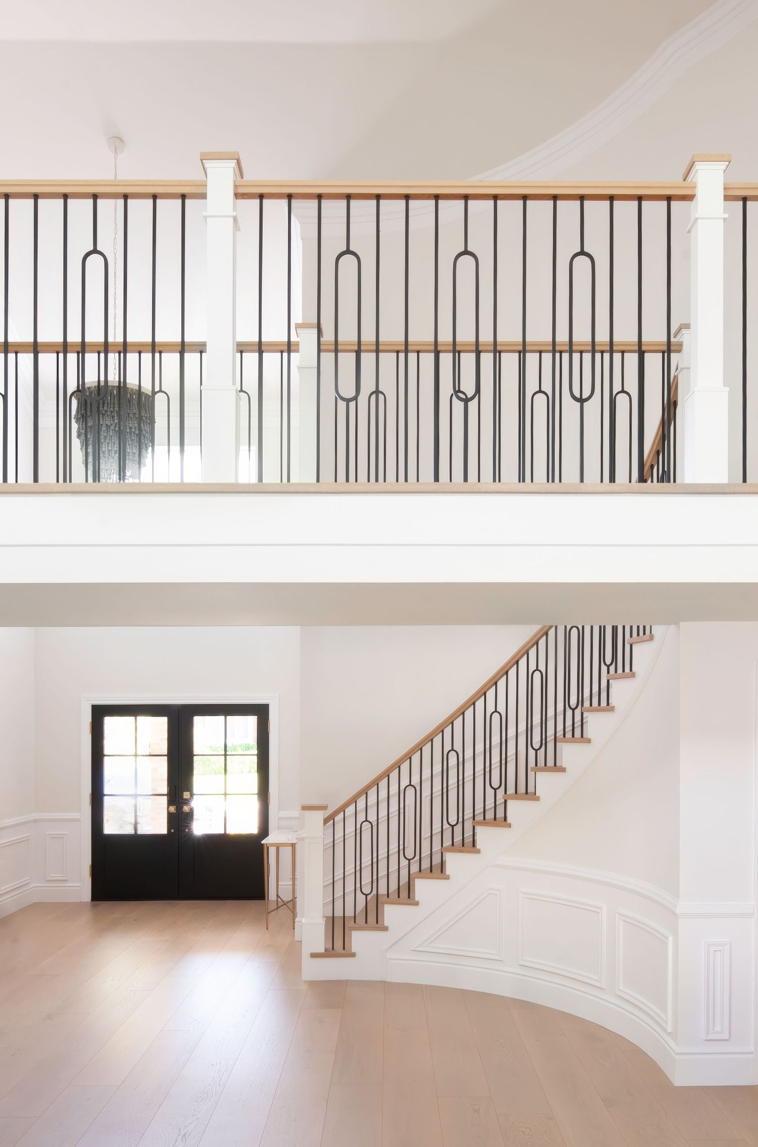 Open concept staircase with contemporary metal balusters and wooden handrail in white interior.