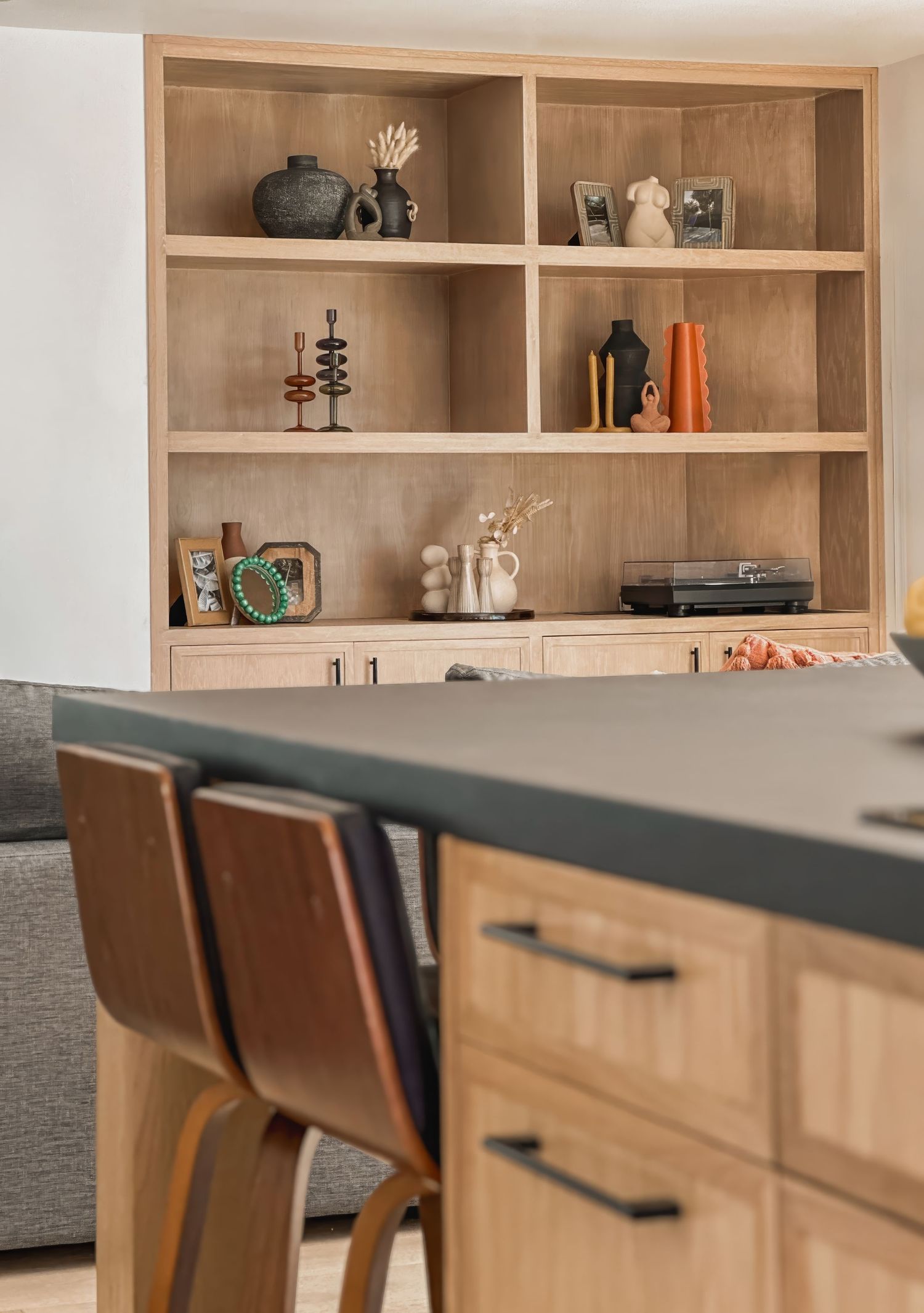 Built-in wooden shelving with decorative items and black counter overhang.