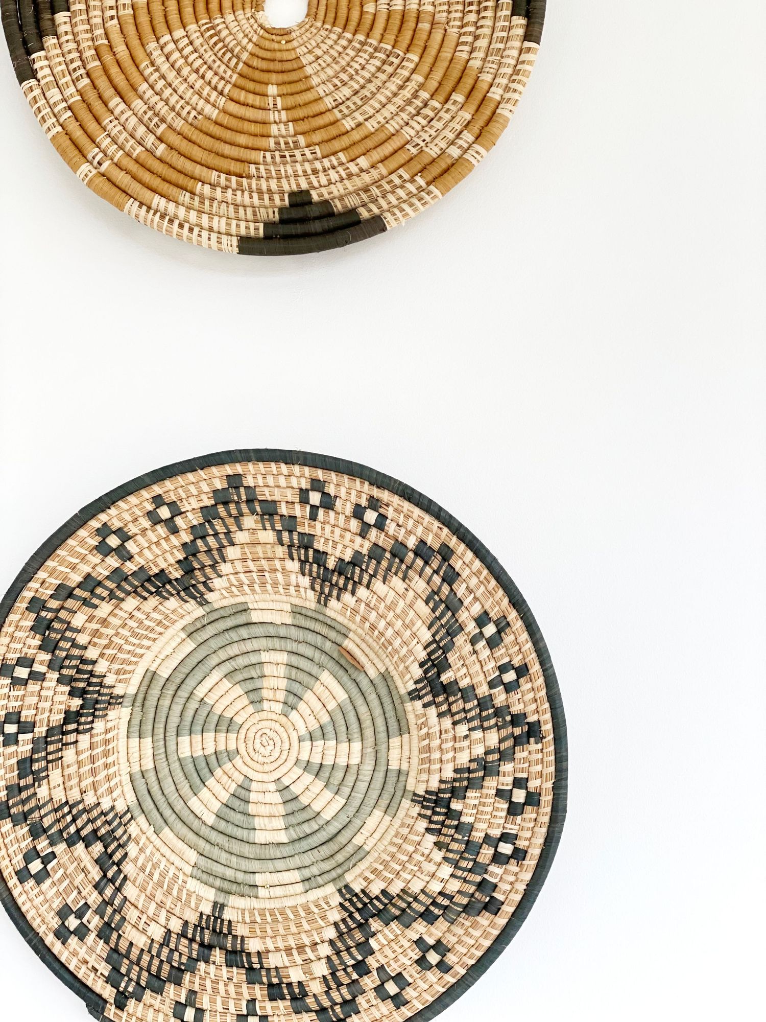 Handwoven natural fiber baskets with intricate black geometric patterns displayed in a row.