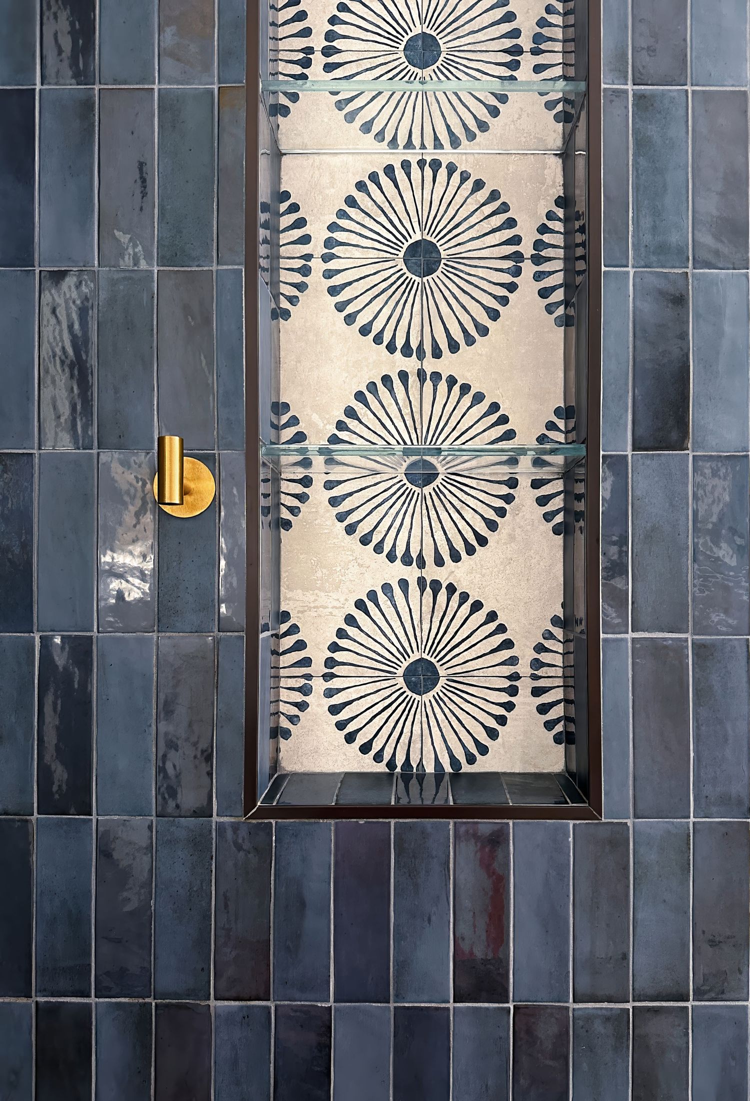 Modern bathroom wall featuring navy blue tiles with white geometric sunburst pattern and gold accents shot by interior designer photographer
