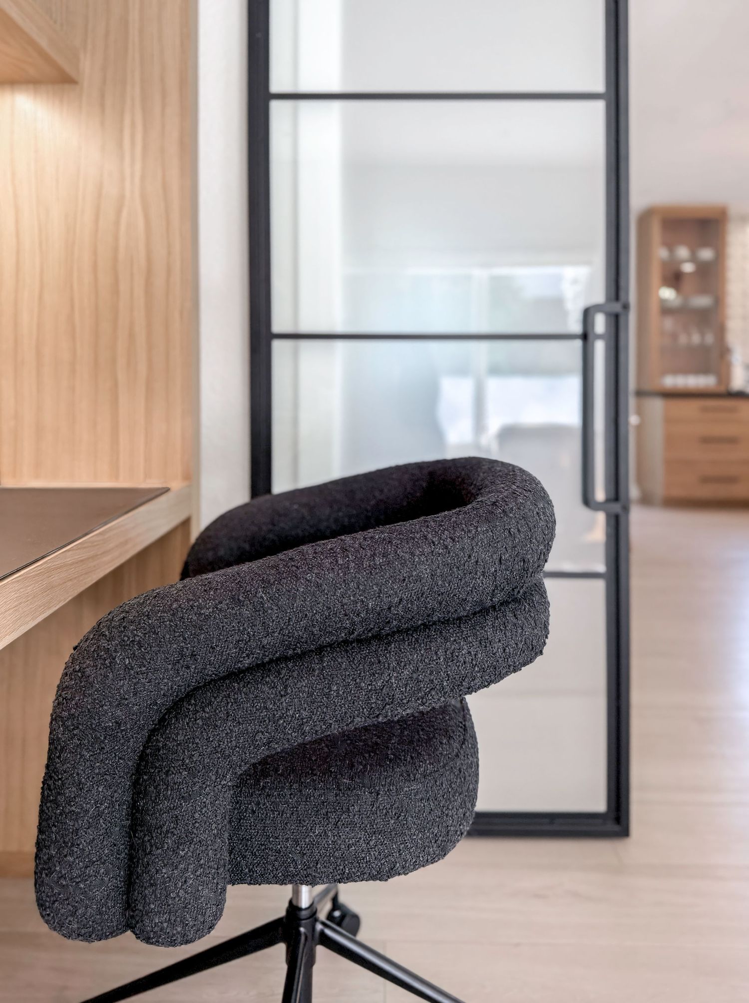Modern office space with dark ergonomic chair, glass door and abundant natural light, photographed by a Southern California photographer.