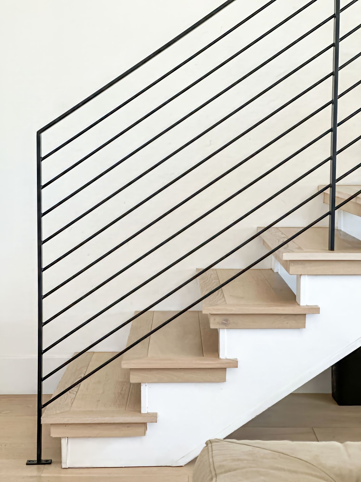 Modern wooden staircase with black metal horizontal railings in contemporary home design.