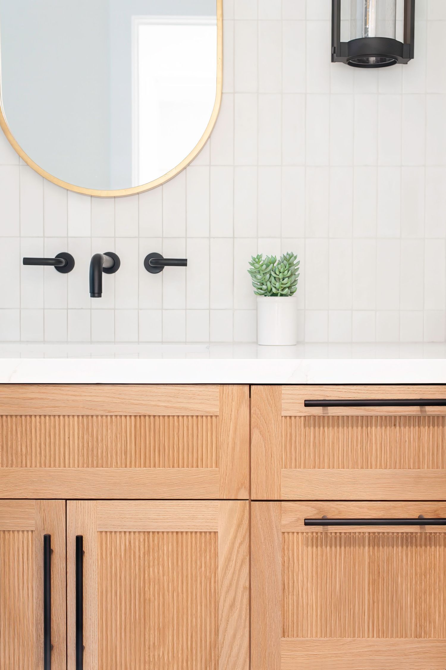 Modern bathroom detail photo showing white tile walls, wooden cabinets, and matte black hardware by a SoCal interior photographer.