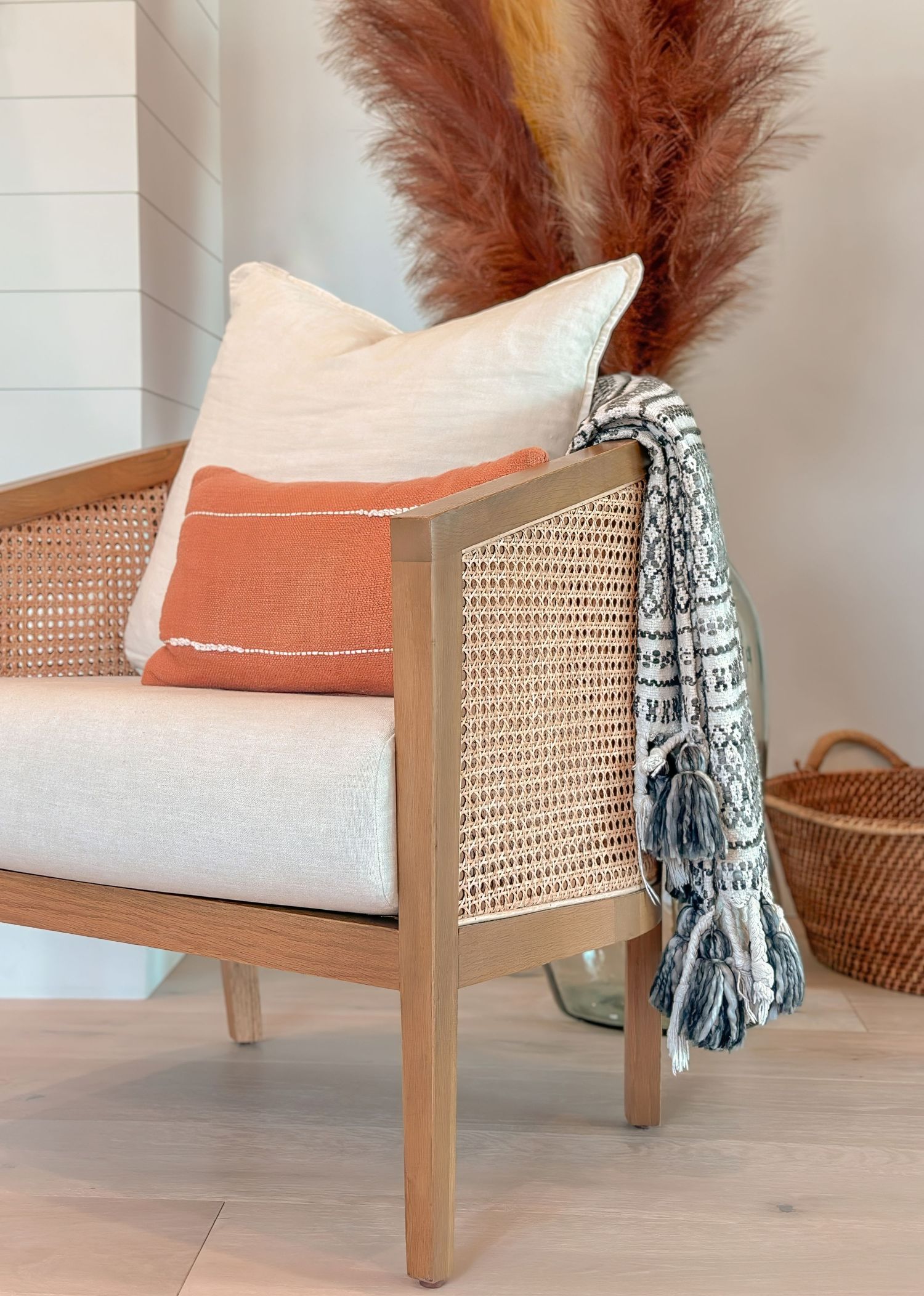 Interior vignette of cane accent chair with coral cushions in contemporary bedroom photographed by interior photographer in Orange County CA