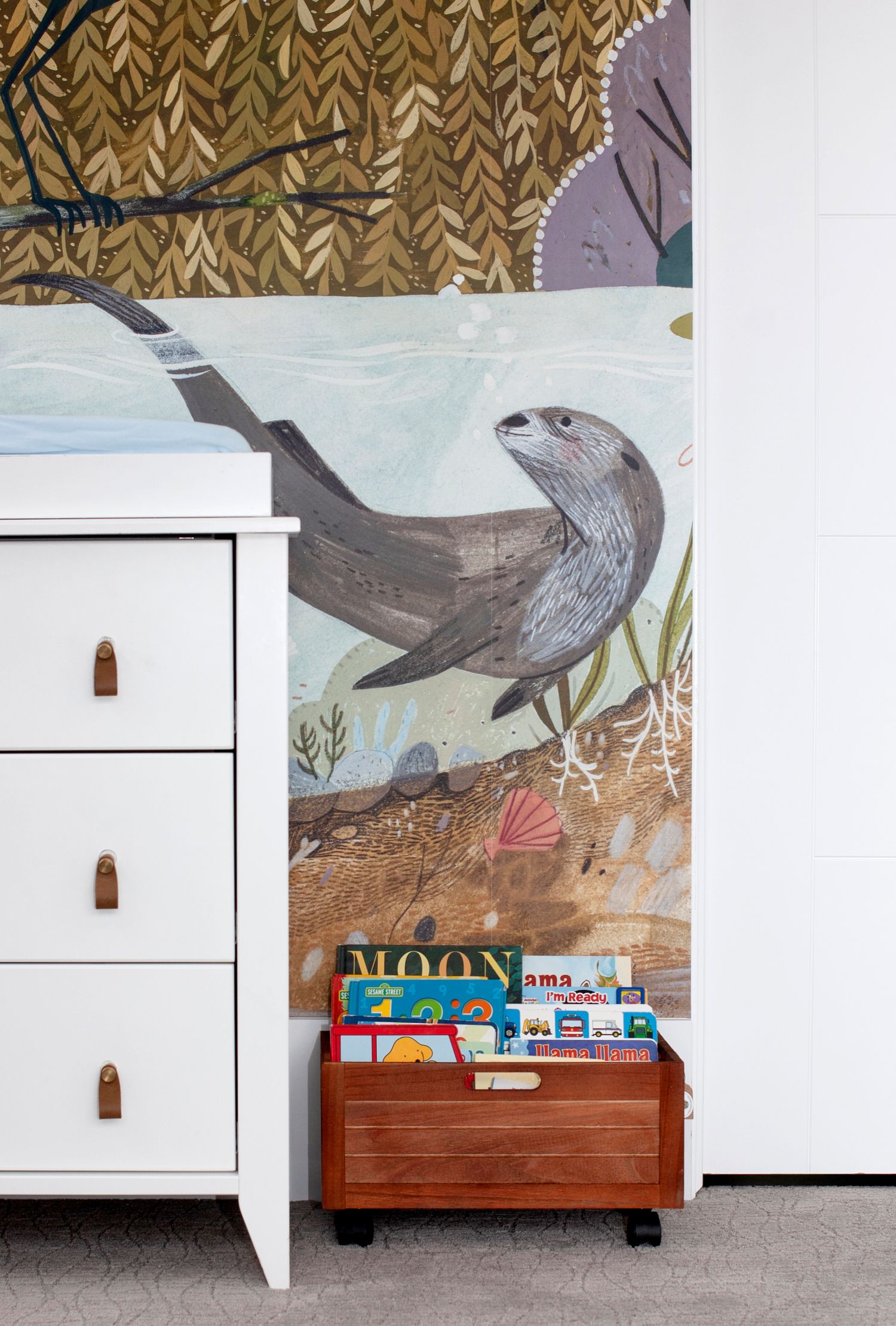 White dresser and wooden bookshelf against a wall with bird and nature-themed mural artwork.