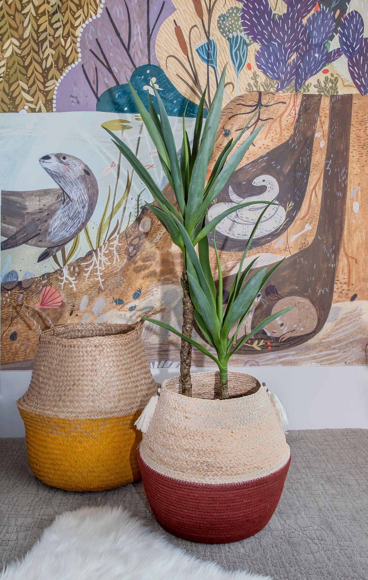 Colorful woven baskets with plants displayed against a wall with bird mural artwork.
