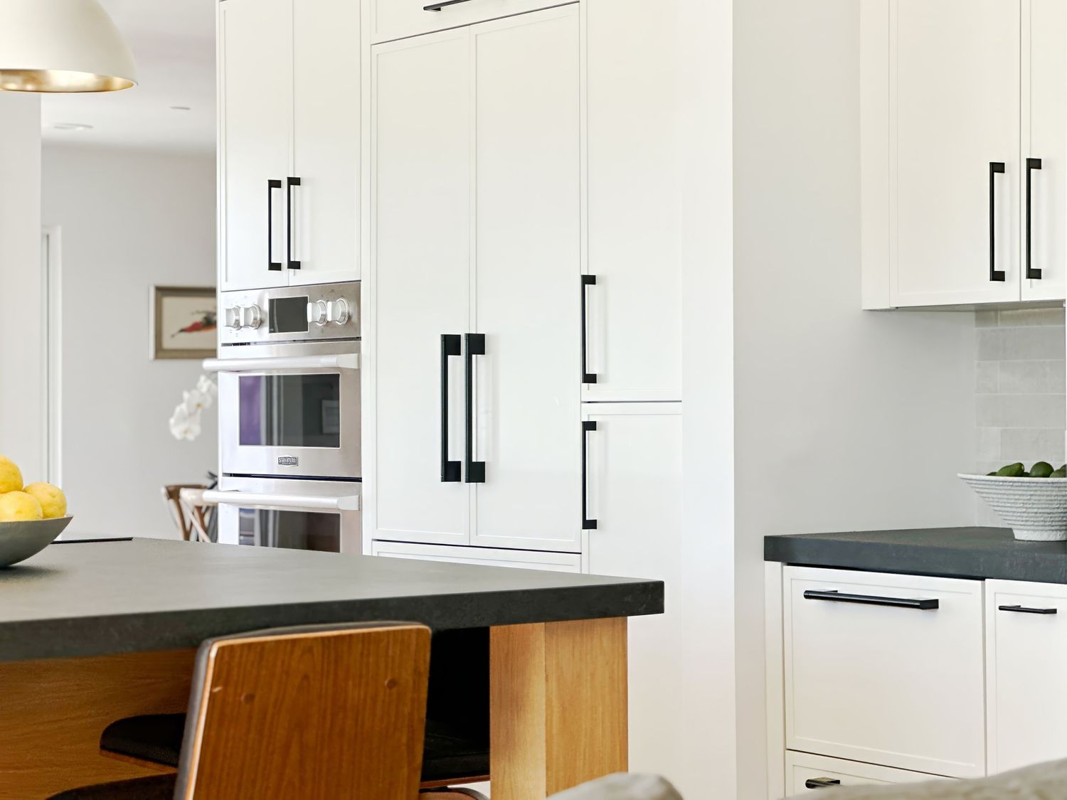 White kitchen cabinets with black handles and wooden accent panels.
