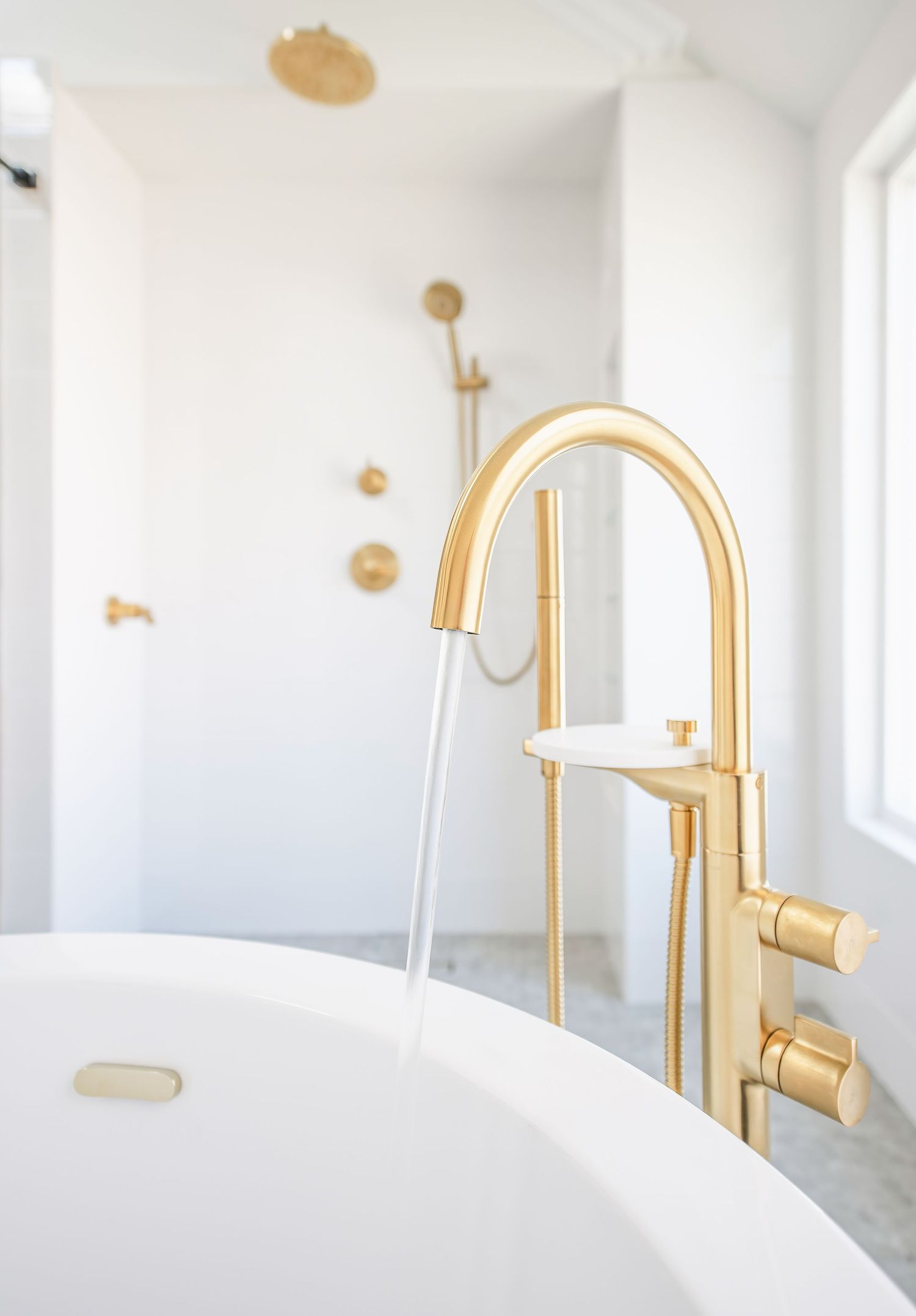Modern white bathroom featuring gold faucets and minimalist design elements.