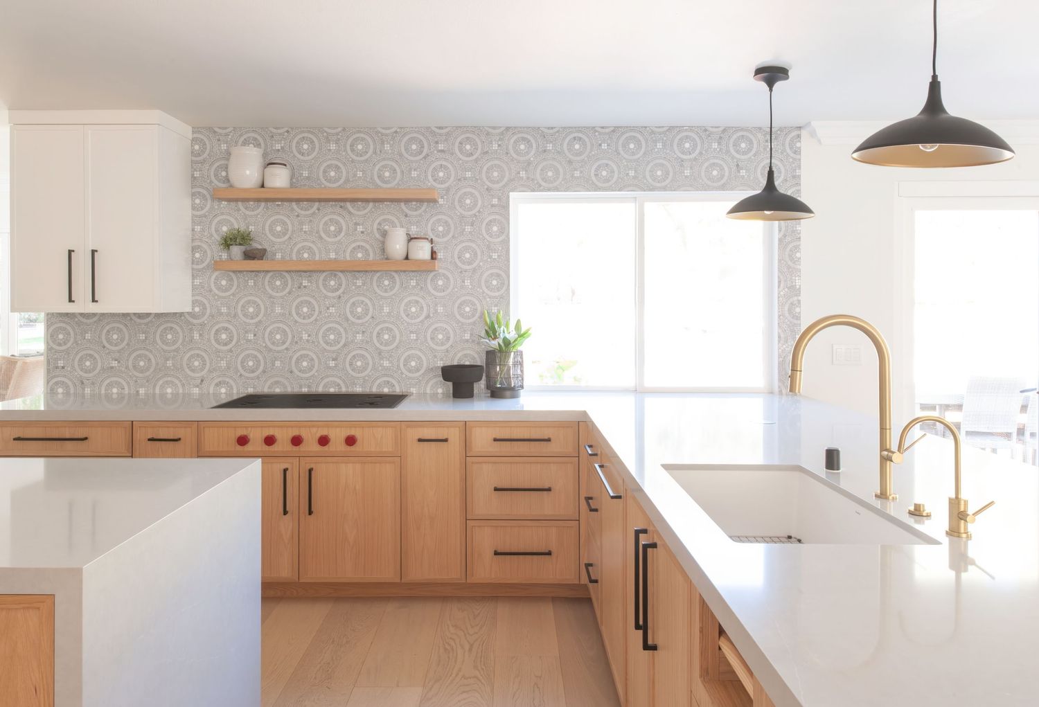 Bright kitchen featuring natural wood cabinets, pendant lights, and geometric wallpaper accent.