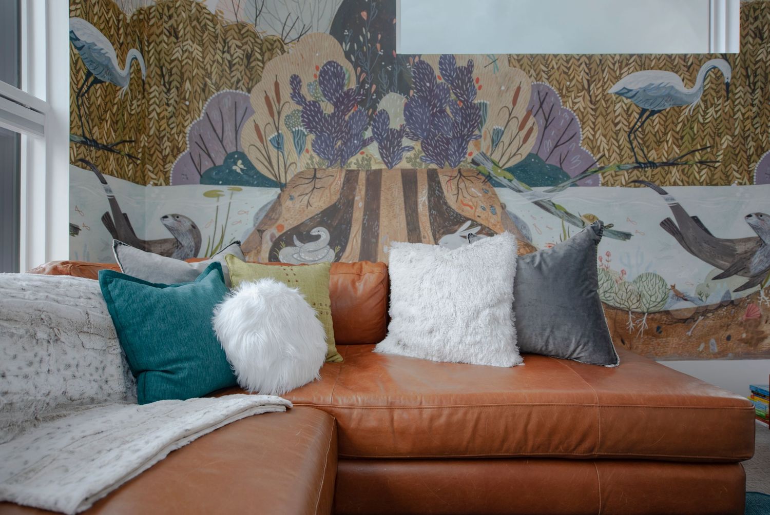 Modern nursery room with white furniture, brown leather chair, and nature-themed wall mural.