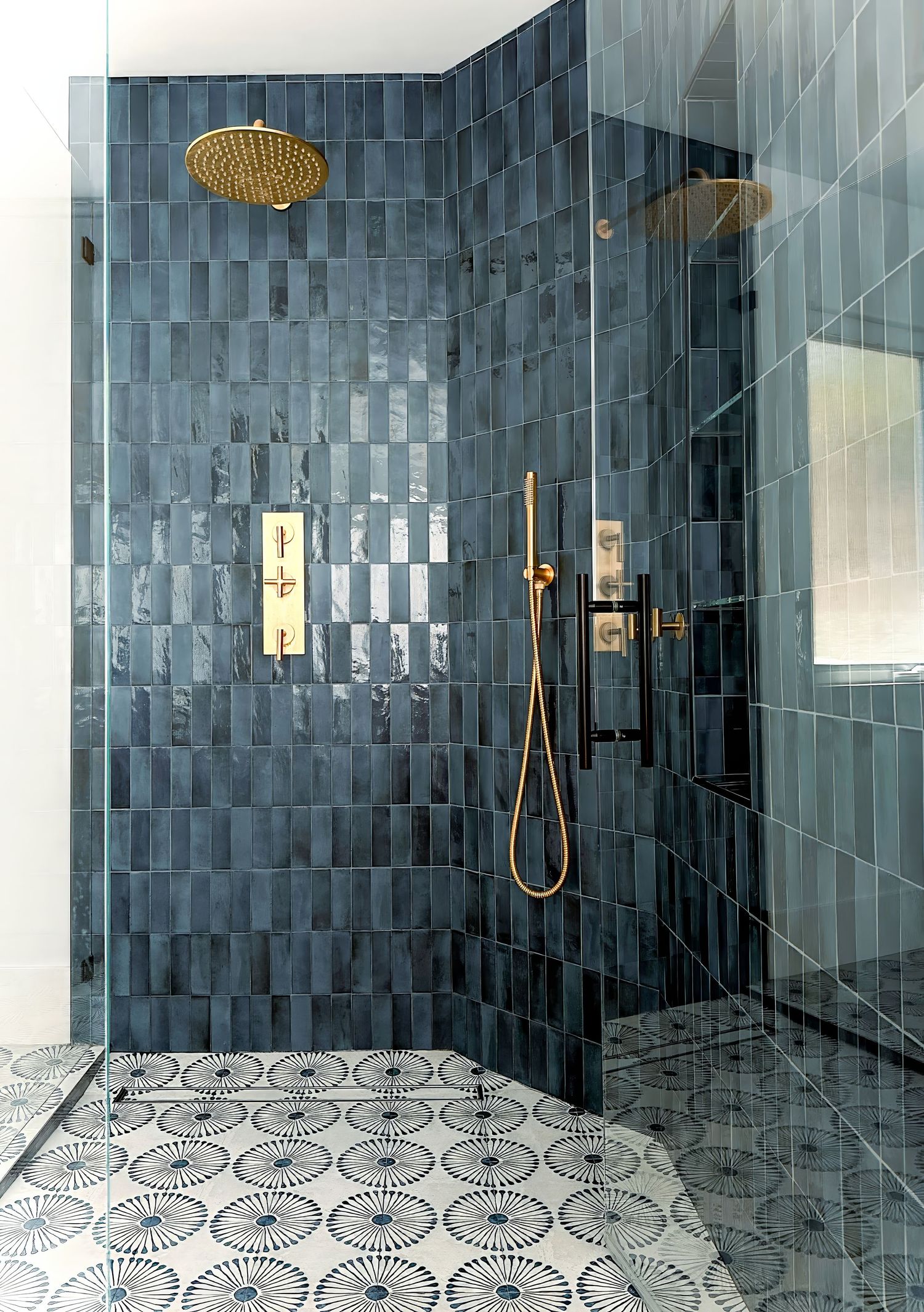 Bathroom photo of luxurious shower room with navy blue tiles, brass fixtures, and geometric floor pattern.